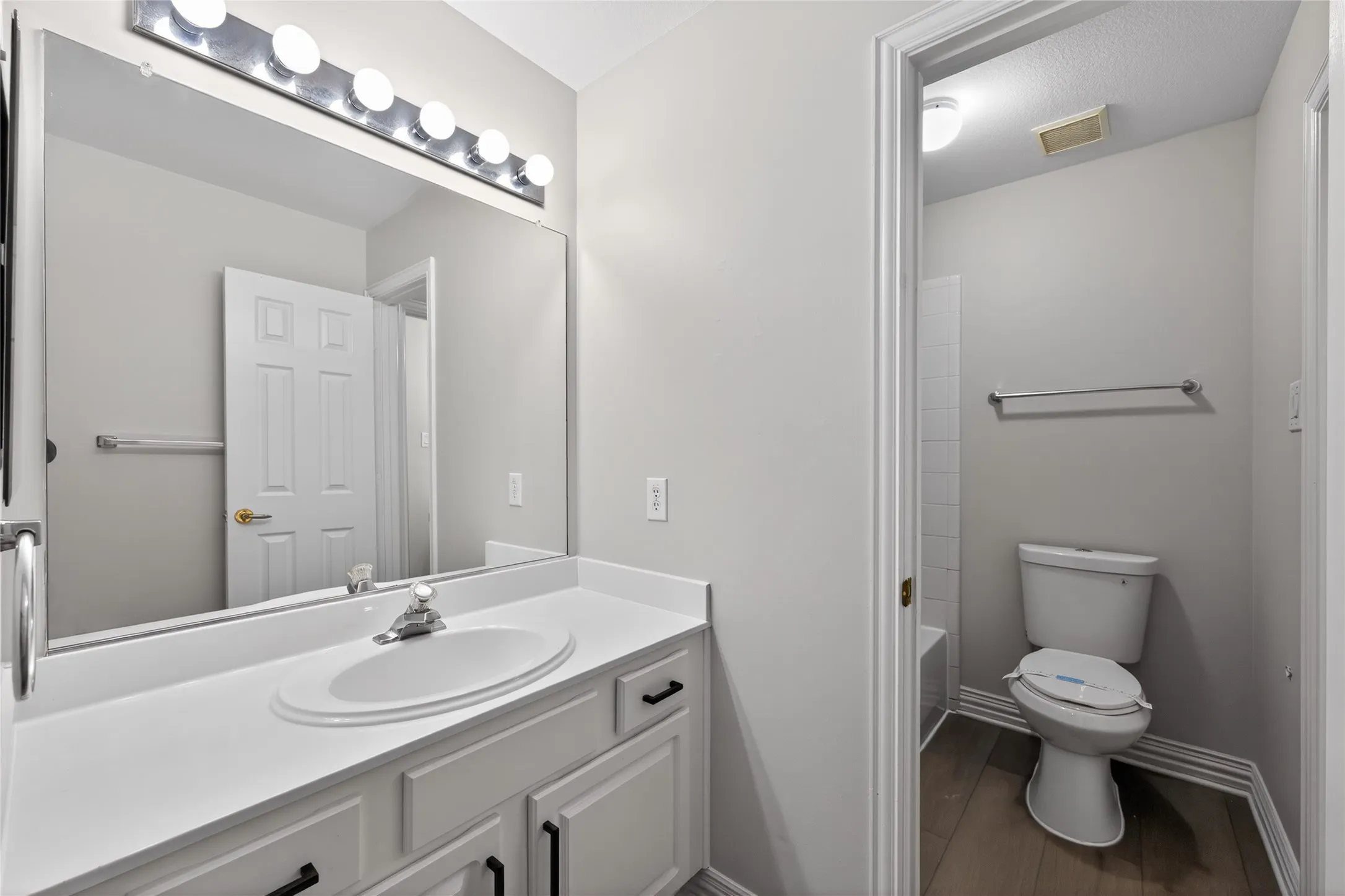 Separate vanity in connecting bathroom featuring an integrated sink, white countertop, and white cabinetry with black hardware
