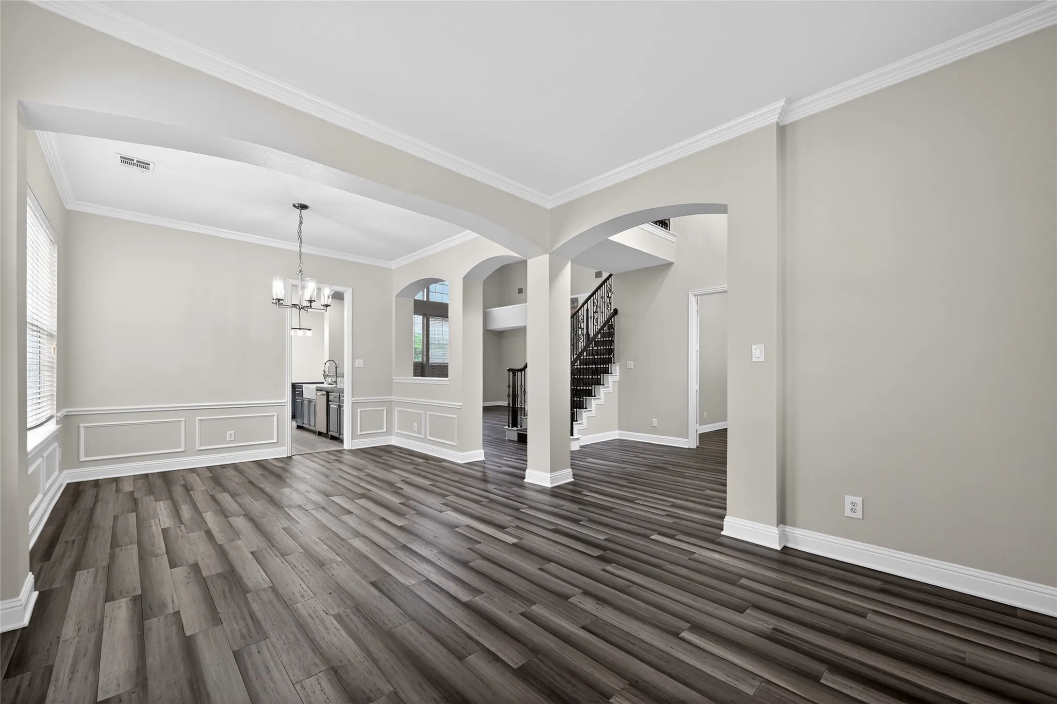 Open concept formal-dining- living space featuring wood-finish flooring and crown molding