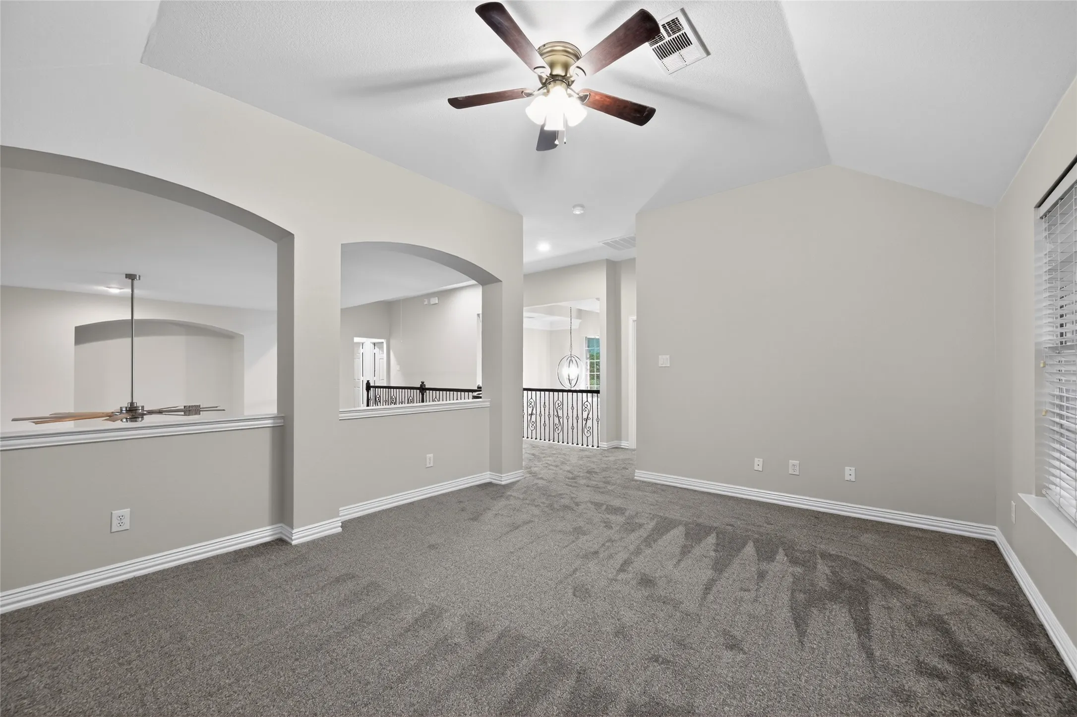 Carpeted loft space with a vaulted ceiling and ceiling fan