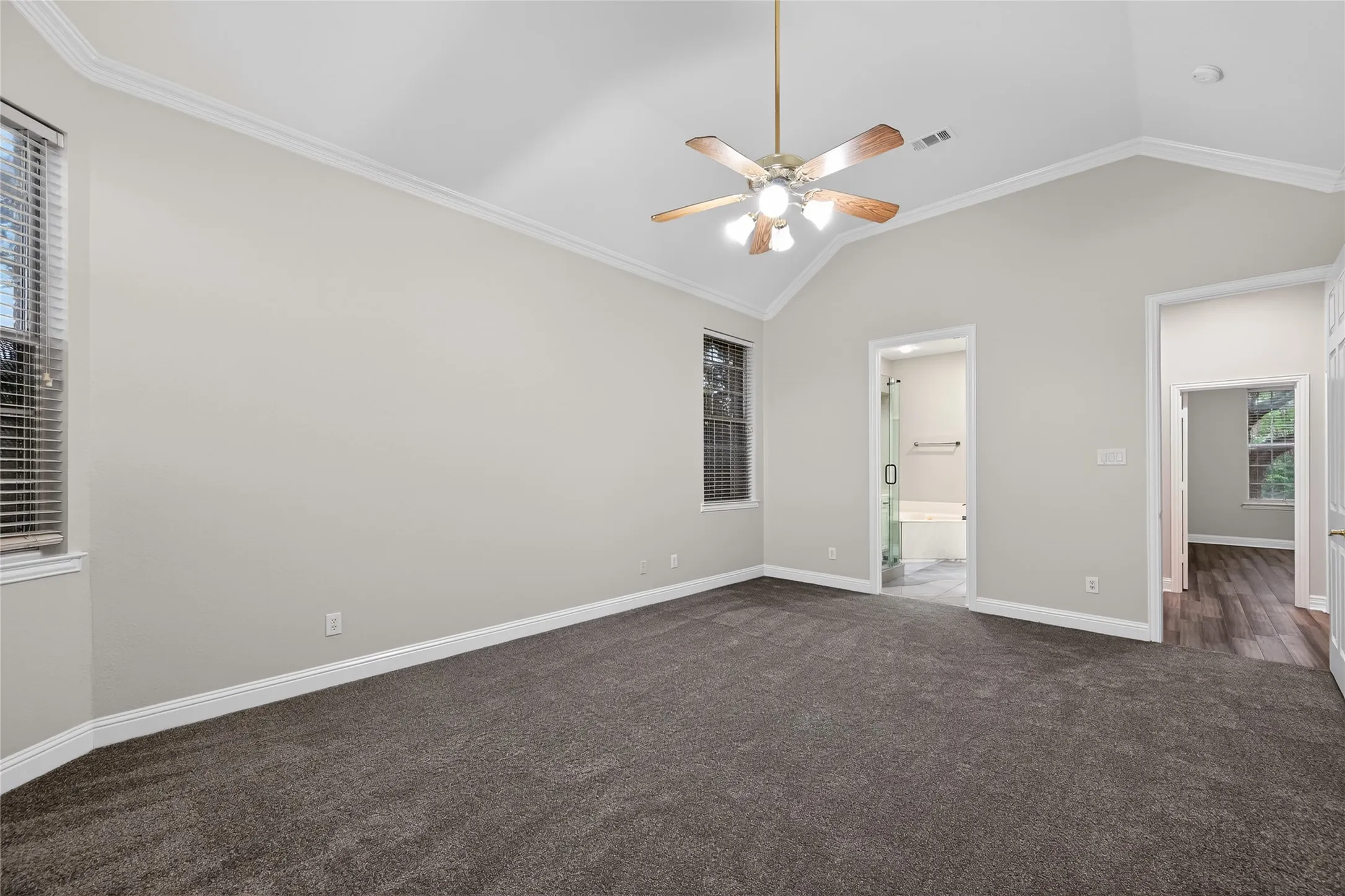 Spacious bedroom featuring vaulted ceilings, a ceiling fan, and carpet flooring