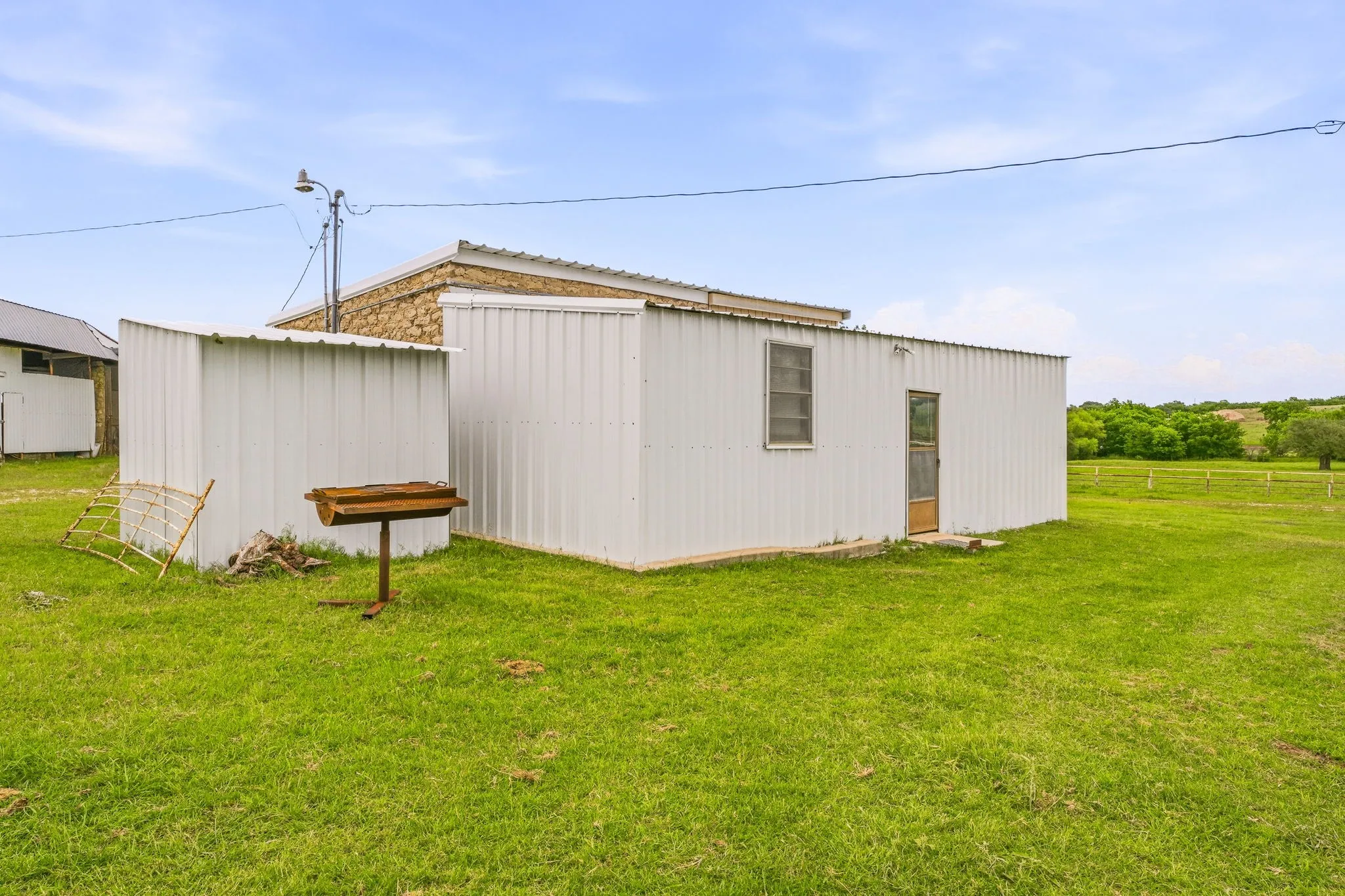Exterior structure featuring corrugated metal siding, a single-pane window, and a wood-paneled door