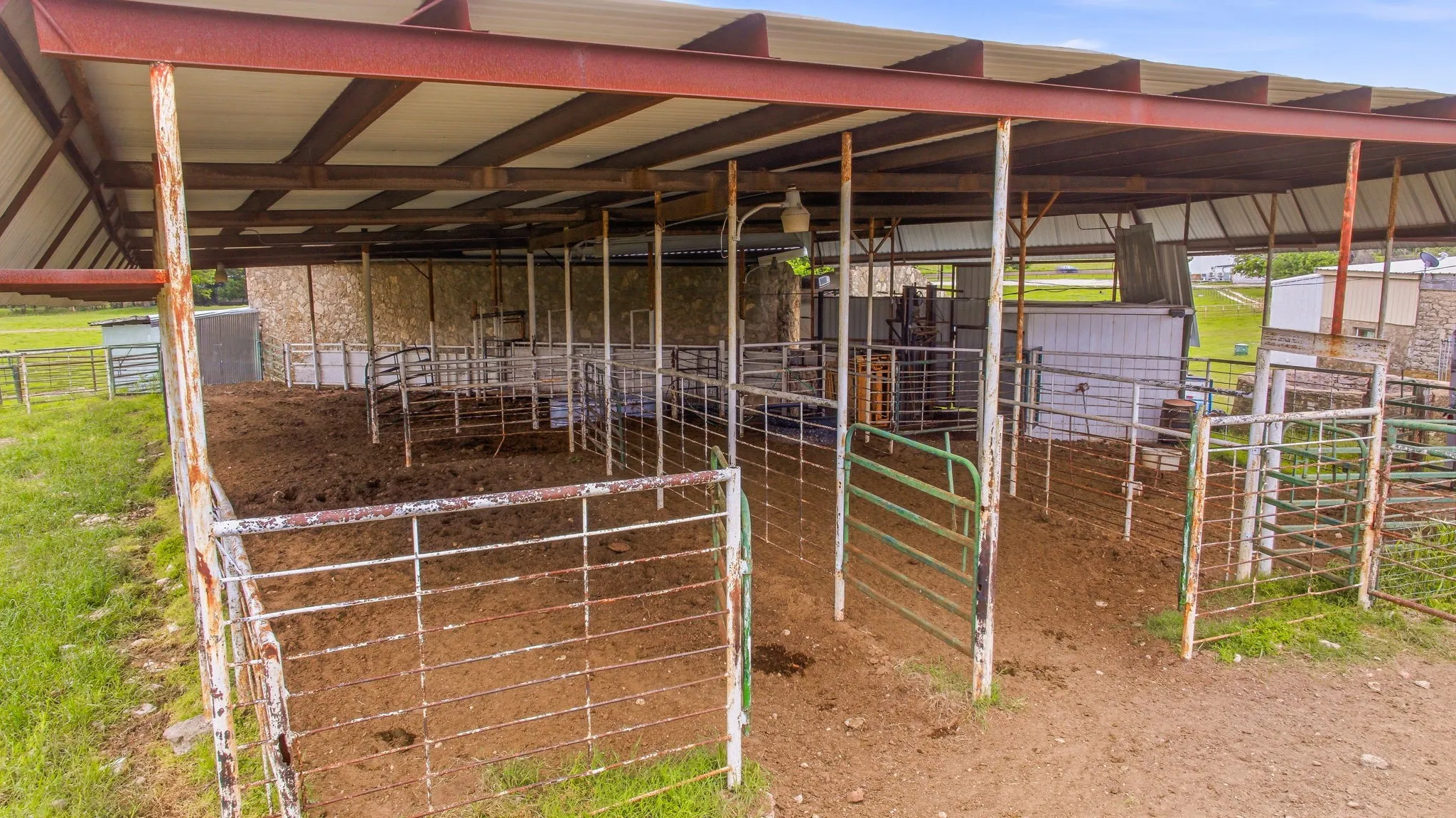 Covered livestock pens featuring multiple sections, metal fencing, and a durable metal roof structure