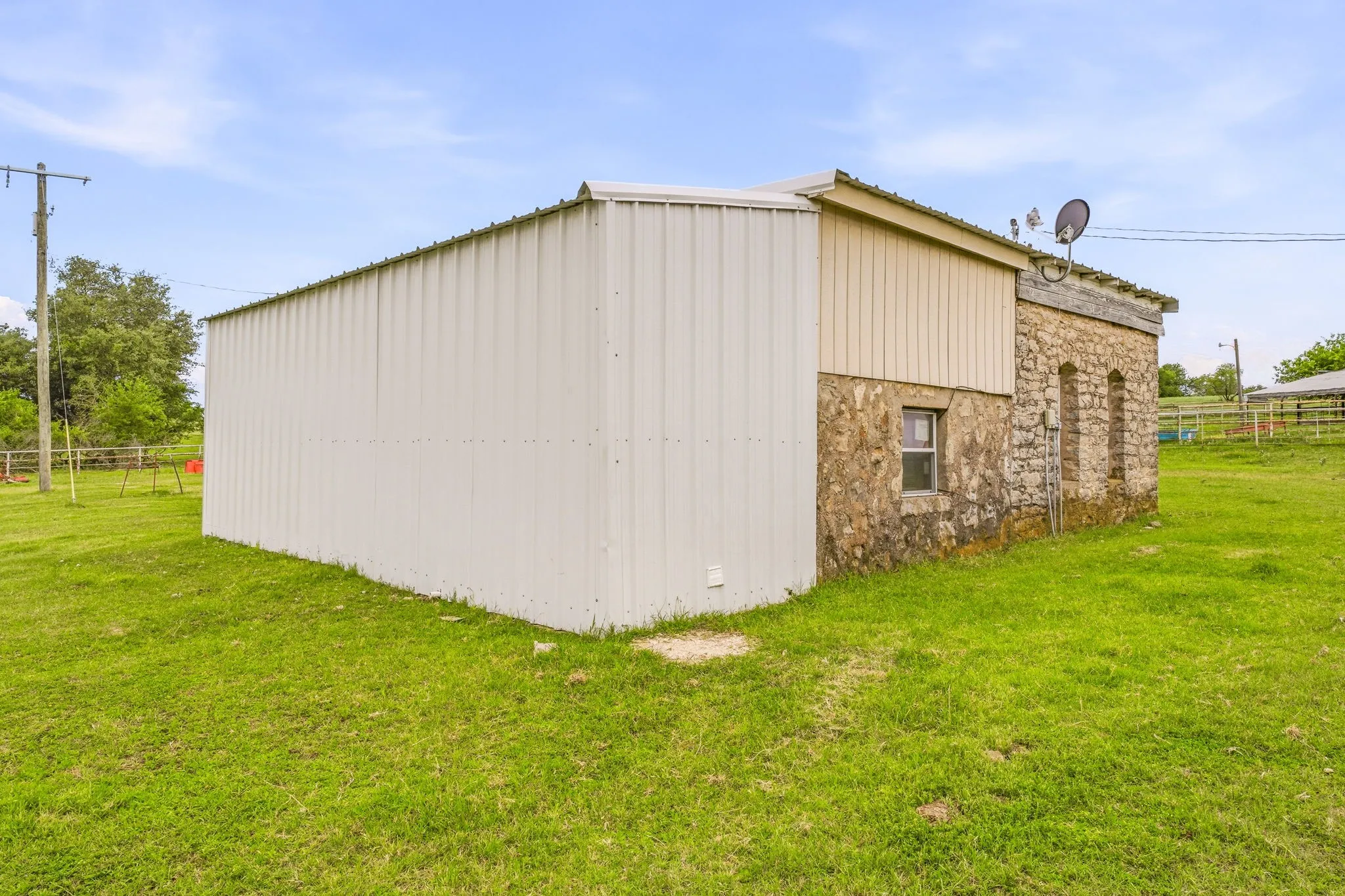 Structure featuring a combination of corrugated metal siding, wood paneling, and stone facade