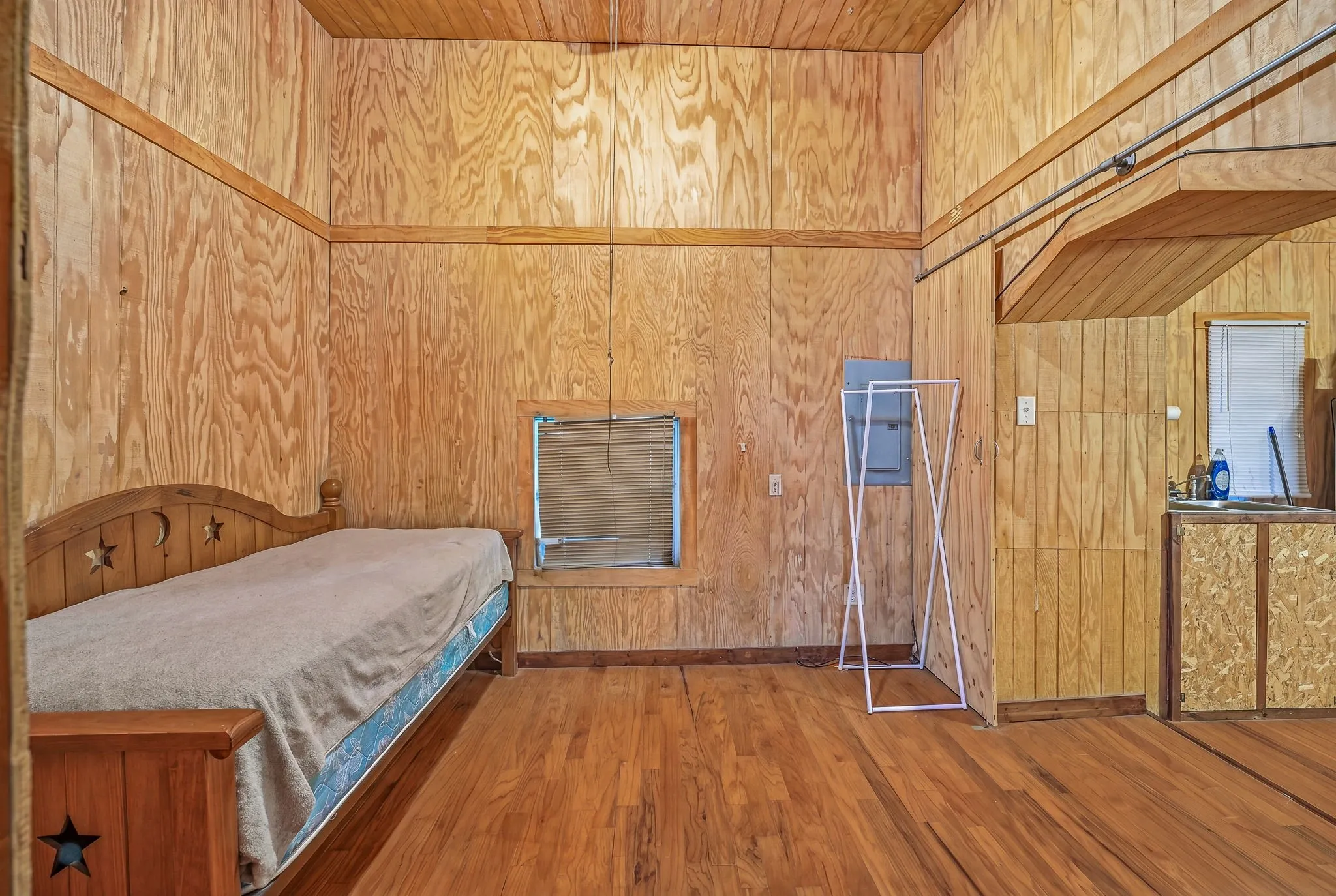 Wood-paneled interior featuring wood-finish flooring, a wood-paneled ceiling, and a built-in window-mounted air conditioning unit