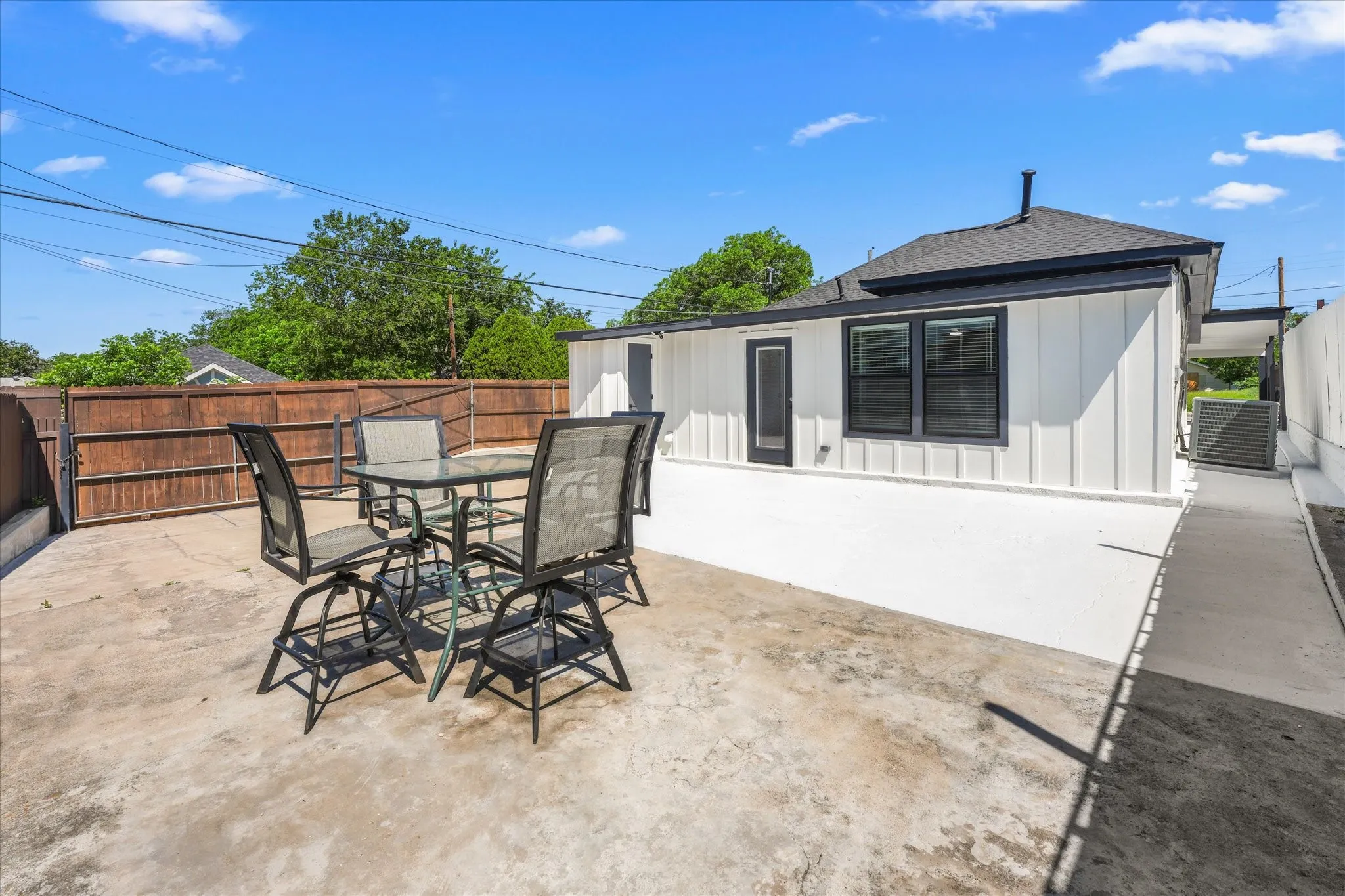 Private outdoor patio with a concrete surface, bordered by a dark wood fence