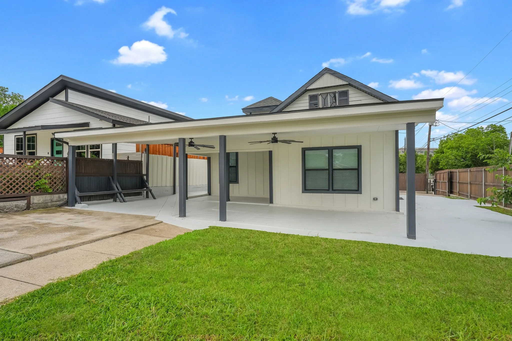 Covered patio with integrated ceiling fans, a concrete surface, and dark support columns