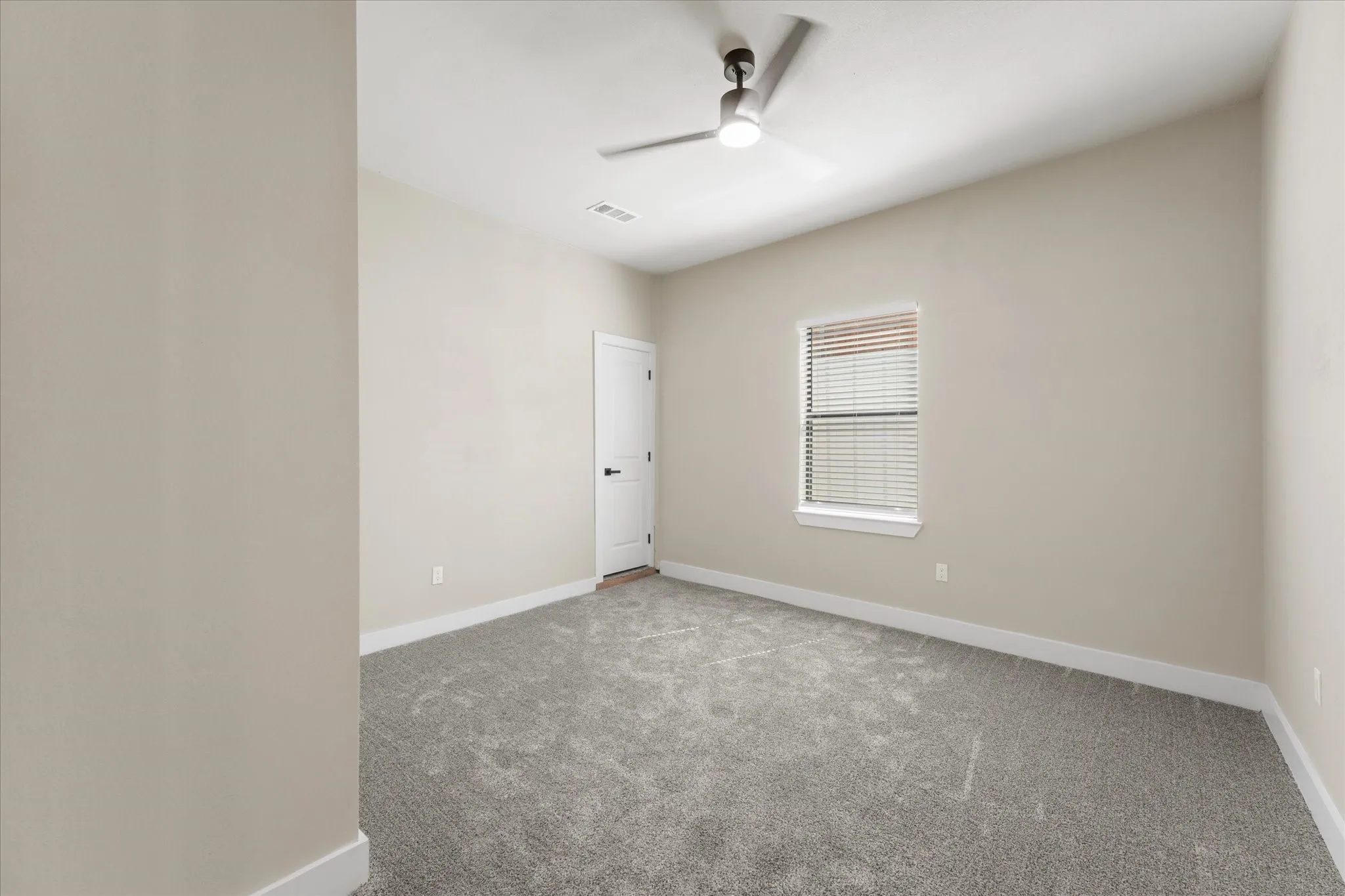 Room #2, Neutral-toned room featuring a single window with blinds, a ceiling fan with integrated lighting, and door with entrance to large attic.