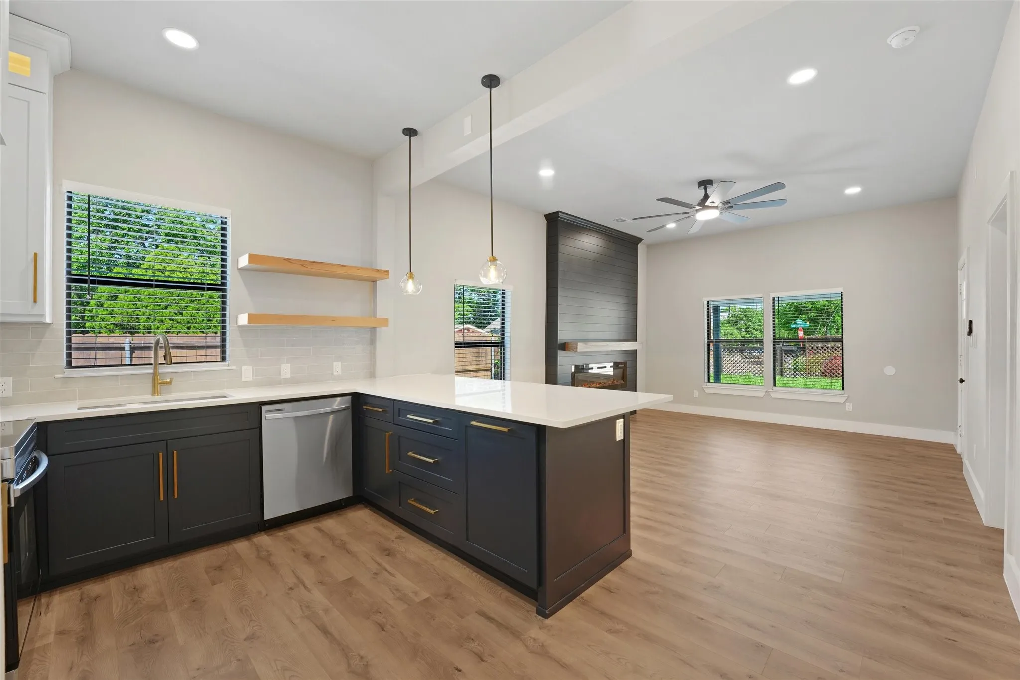 Open-concept living space featuring a kitchen island with seating, a built-in fireplace, recessed lighting, and a ceiling fan