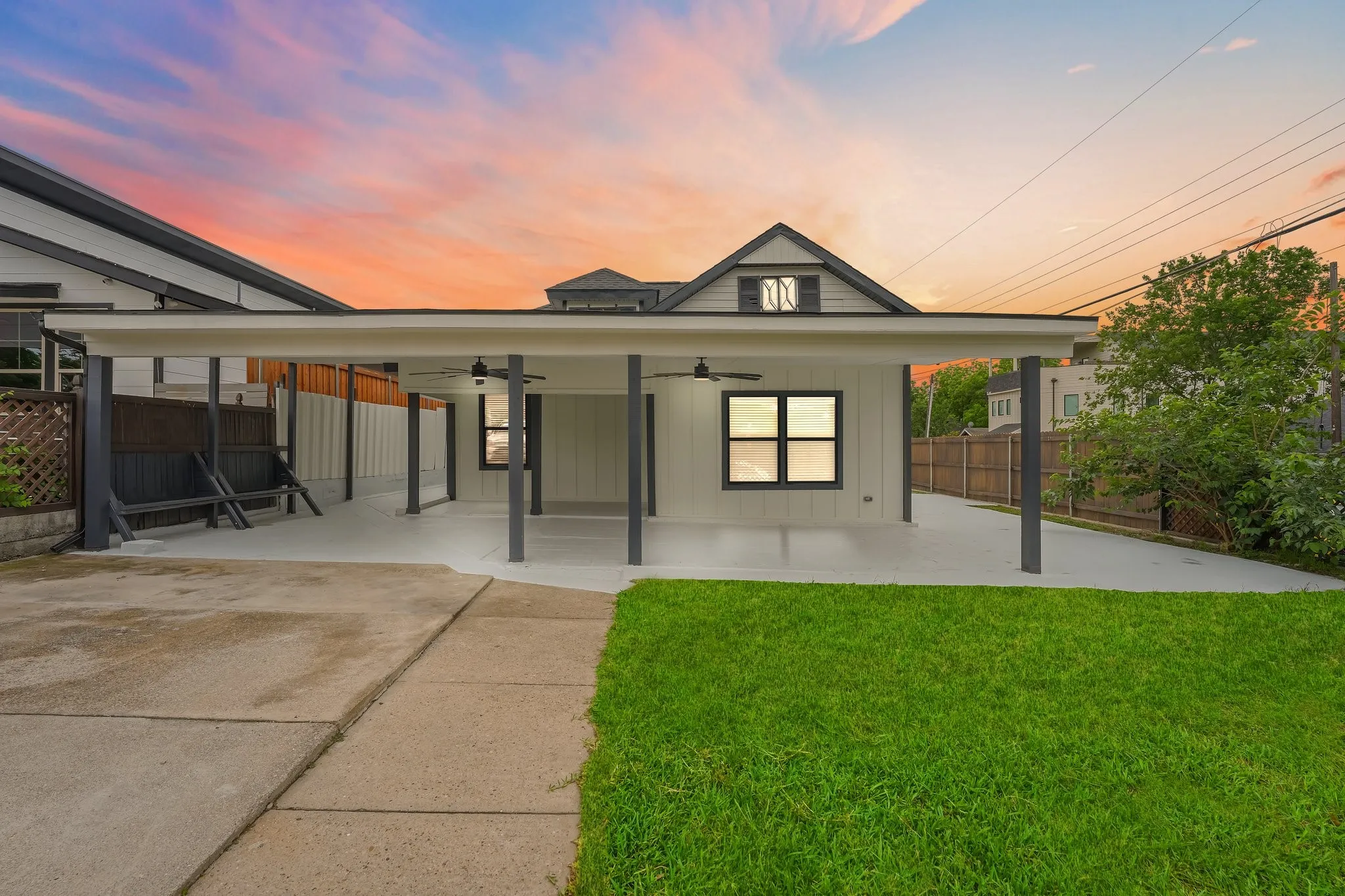Expansive covered patio featuring multiple support columns, dual ceiling fans, and concrete flooring