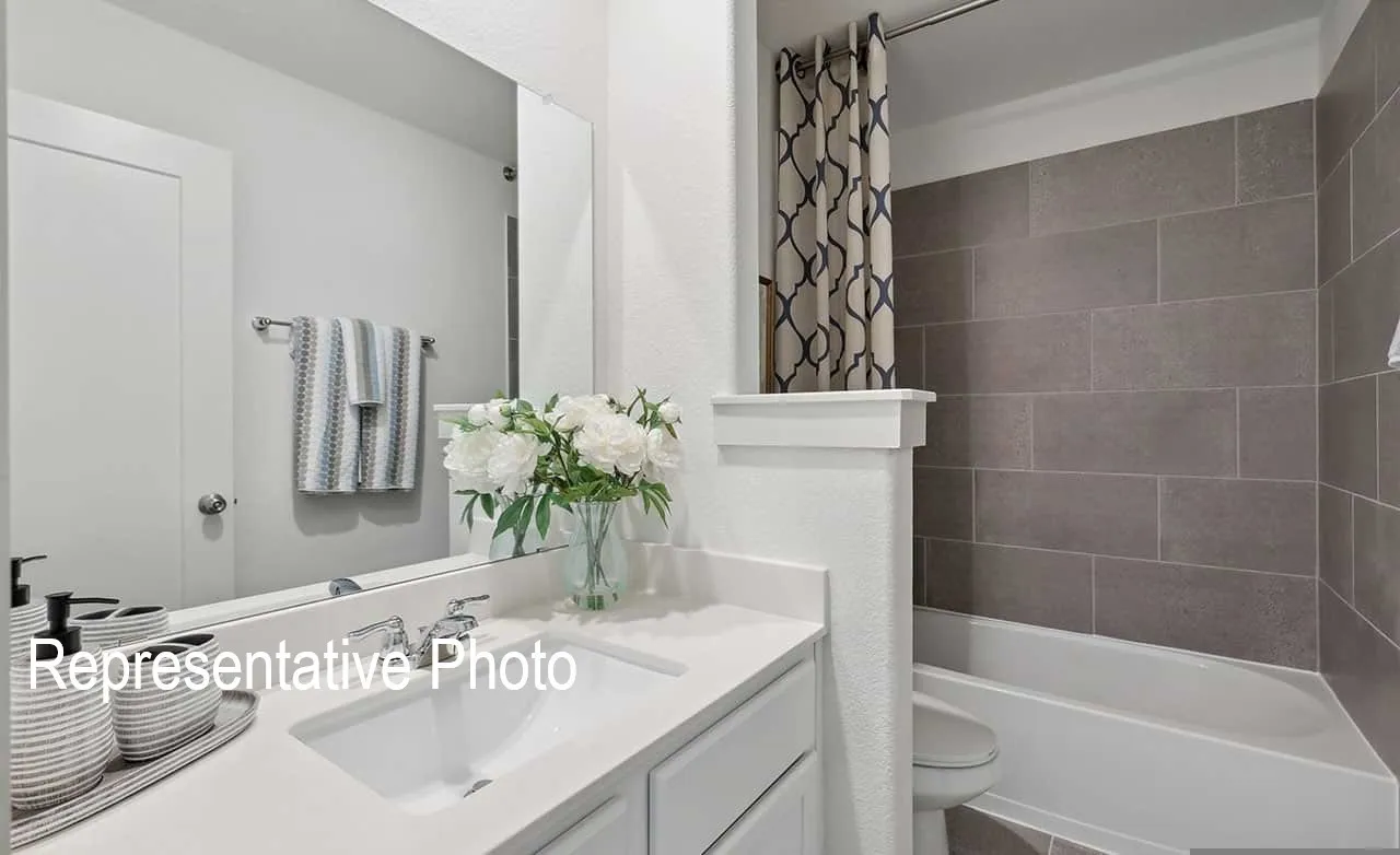 Bathroom featuring a spacious vanity with an integrated sink, polished chrome faucet, and a large wall-mounted mirror