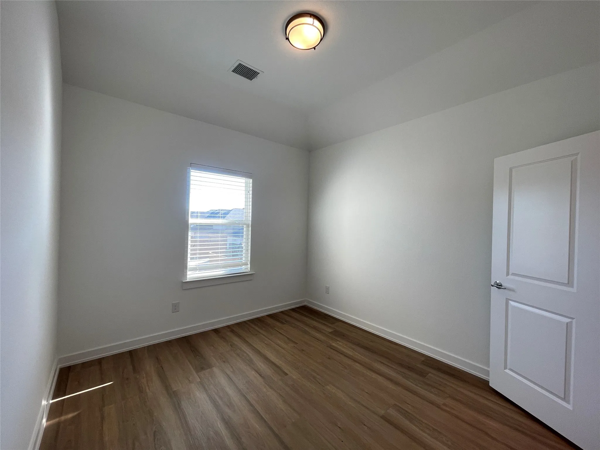 Room with wood-finish flooring, crisp white walls, and a recessed window with​​‌​​​​‌​​‌‌​‌‌​​​‌‌​‌​‌​‌​​​‌​​ blinds