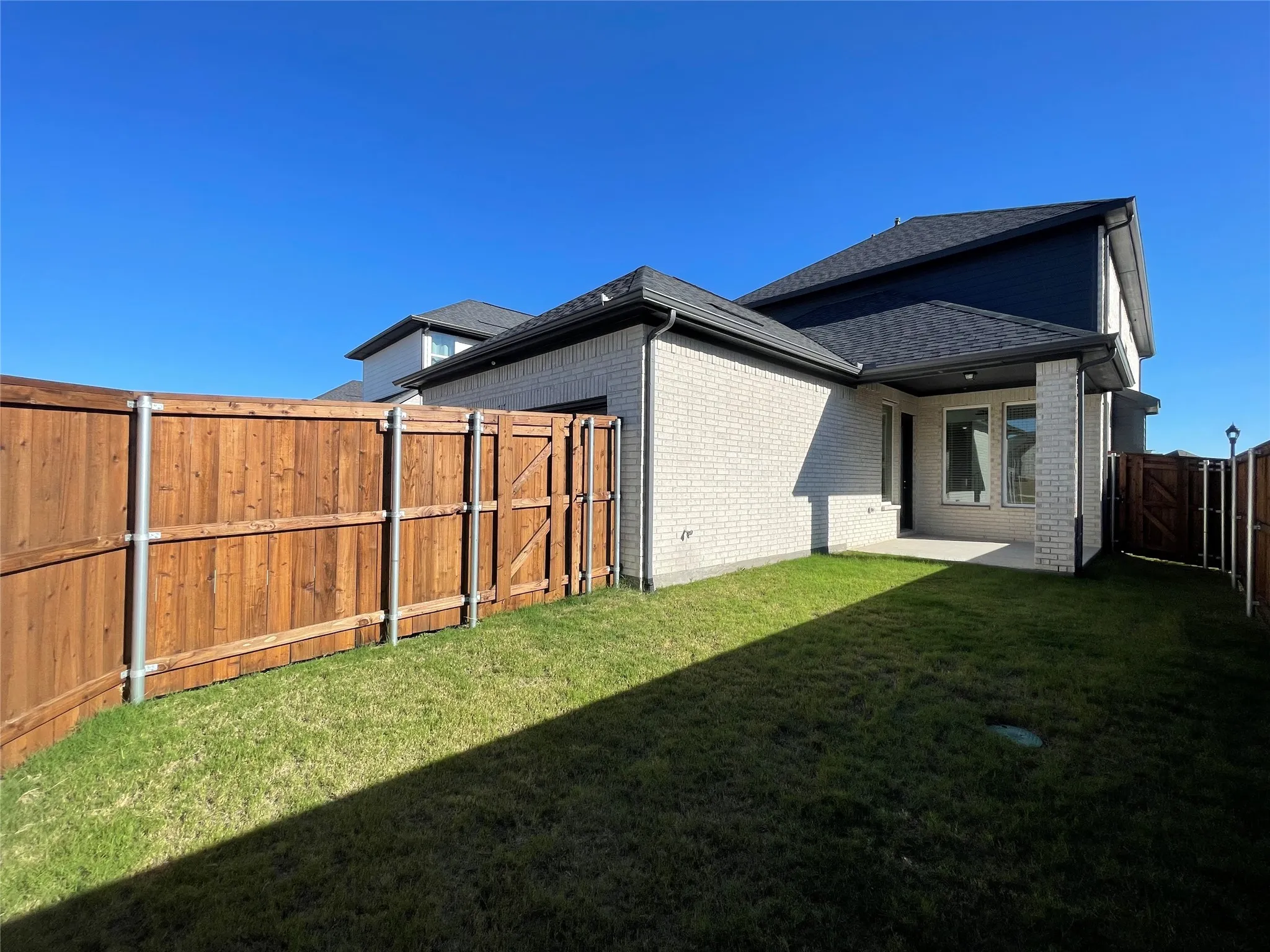 Expansive grassy backyard featuring a full privacy fence with a side gate
