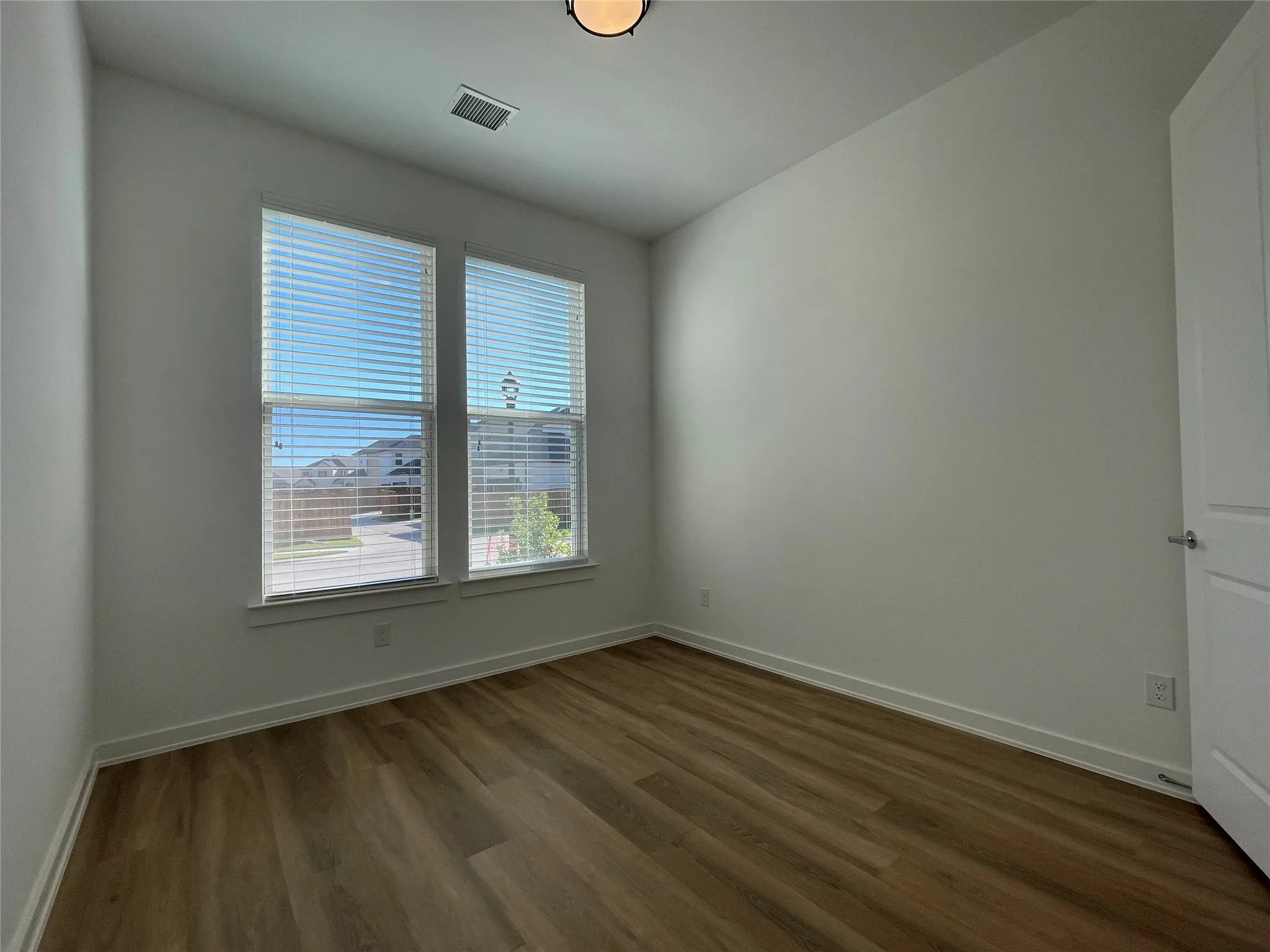 Interior room featuring wood-finish flooring, white baseboards, and neutral wall paint