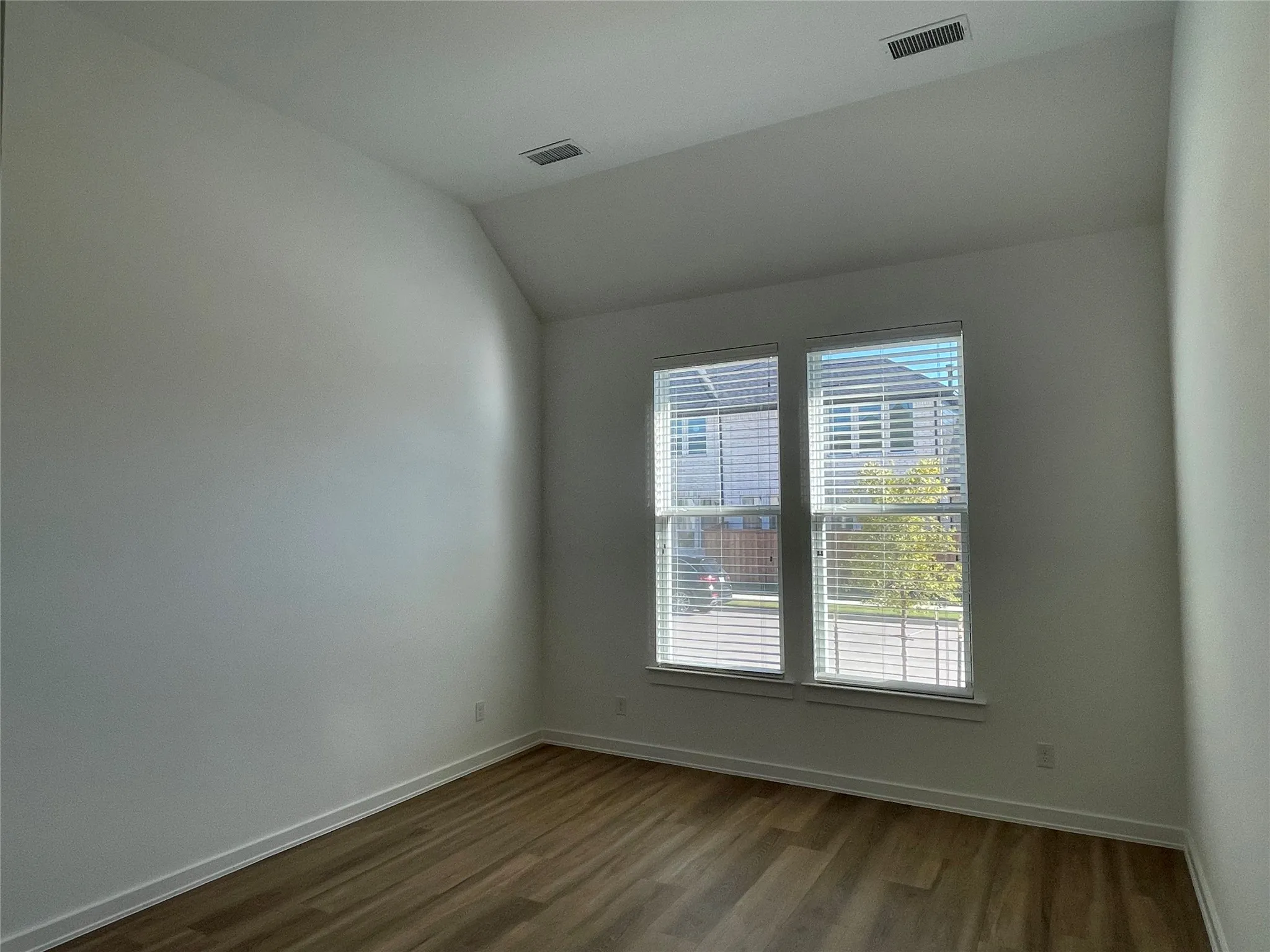 Room featuring wood-finish flooring, white baseboards, and neutral wall paint
