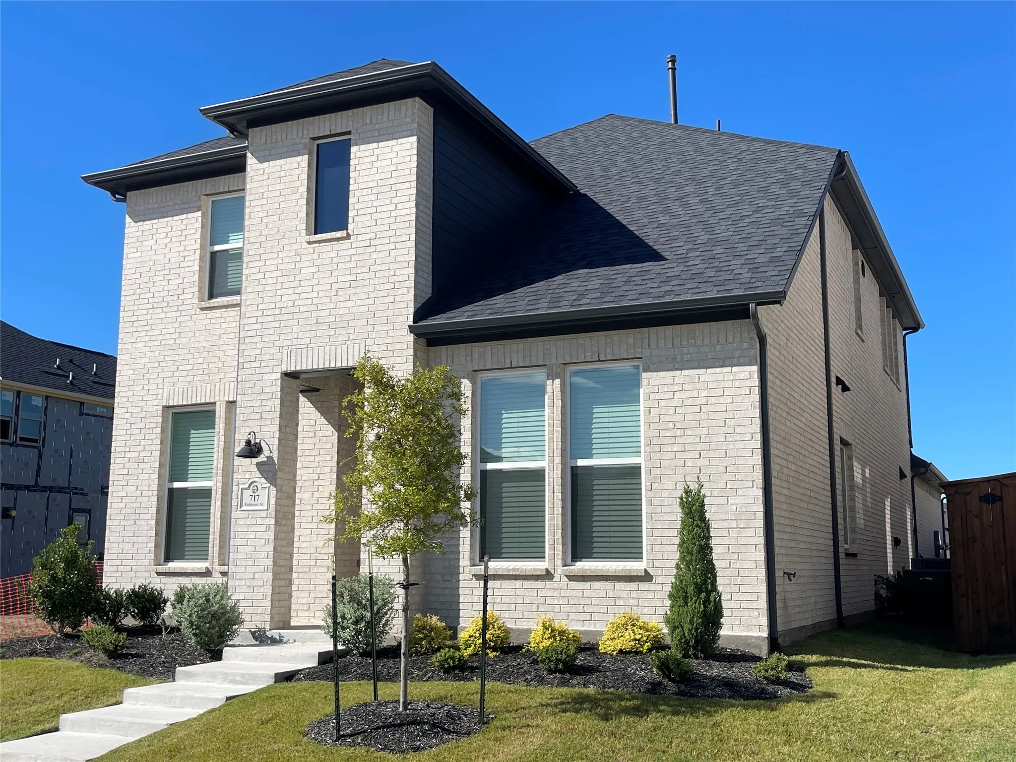 Contemporary two-story residence featuring light brick masonry and dark trim details