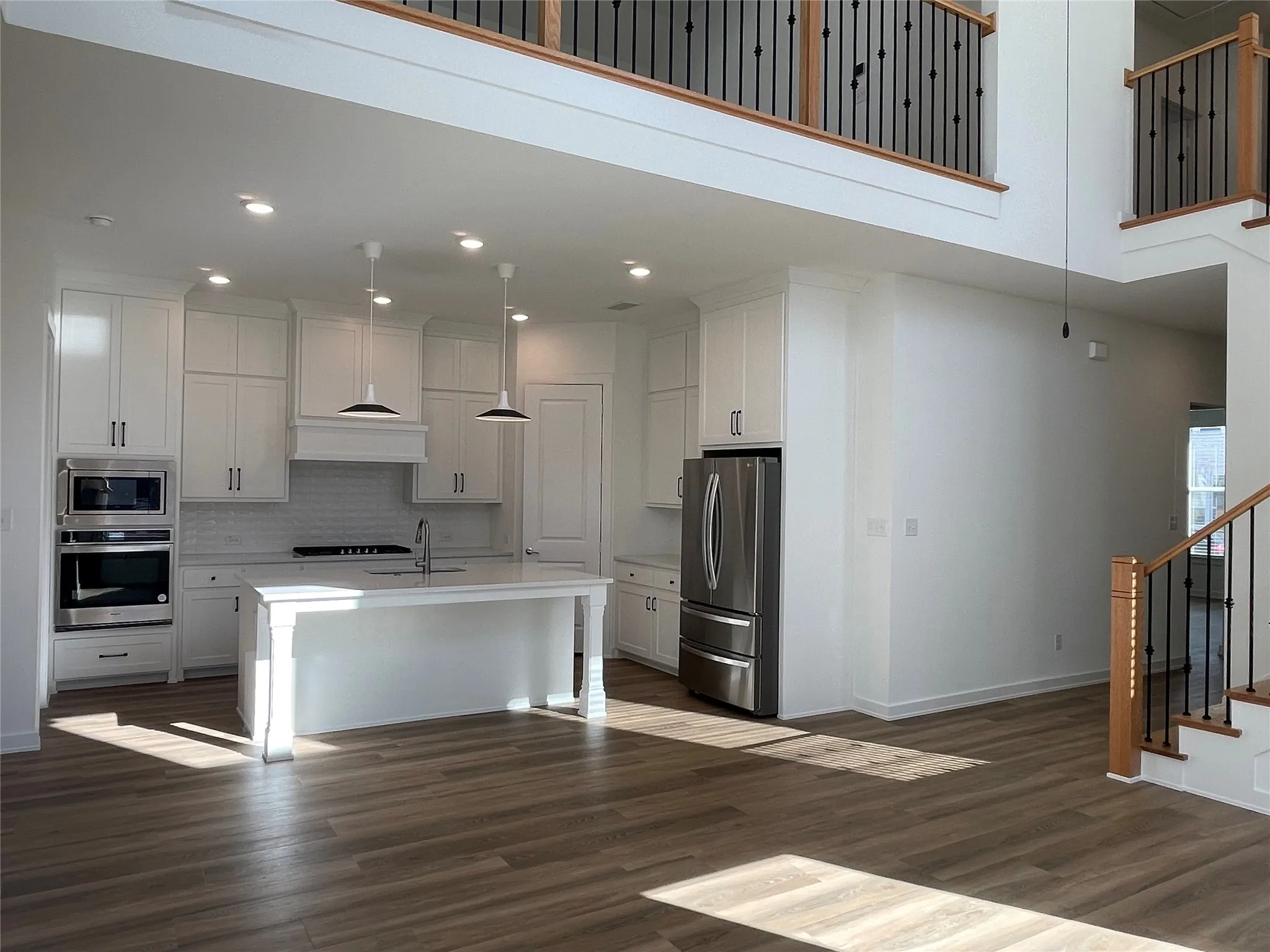 Open-concept living area featuring a modern kitchen with white cabinetry, stainless steel appliances, and an island with seating