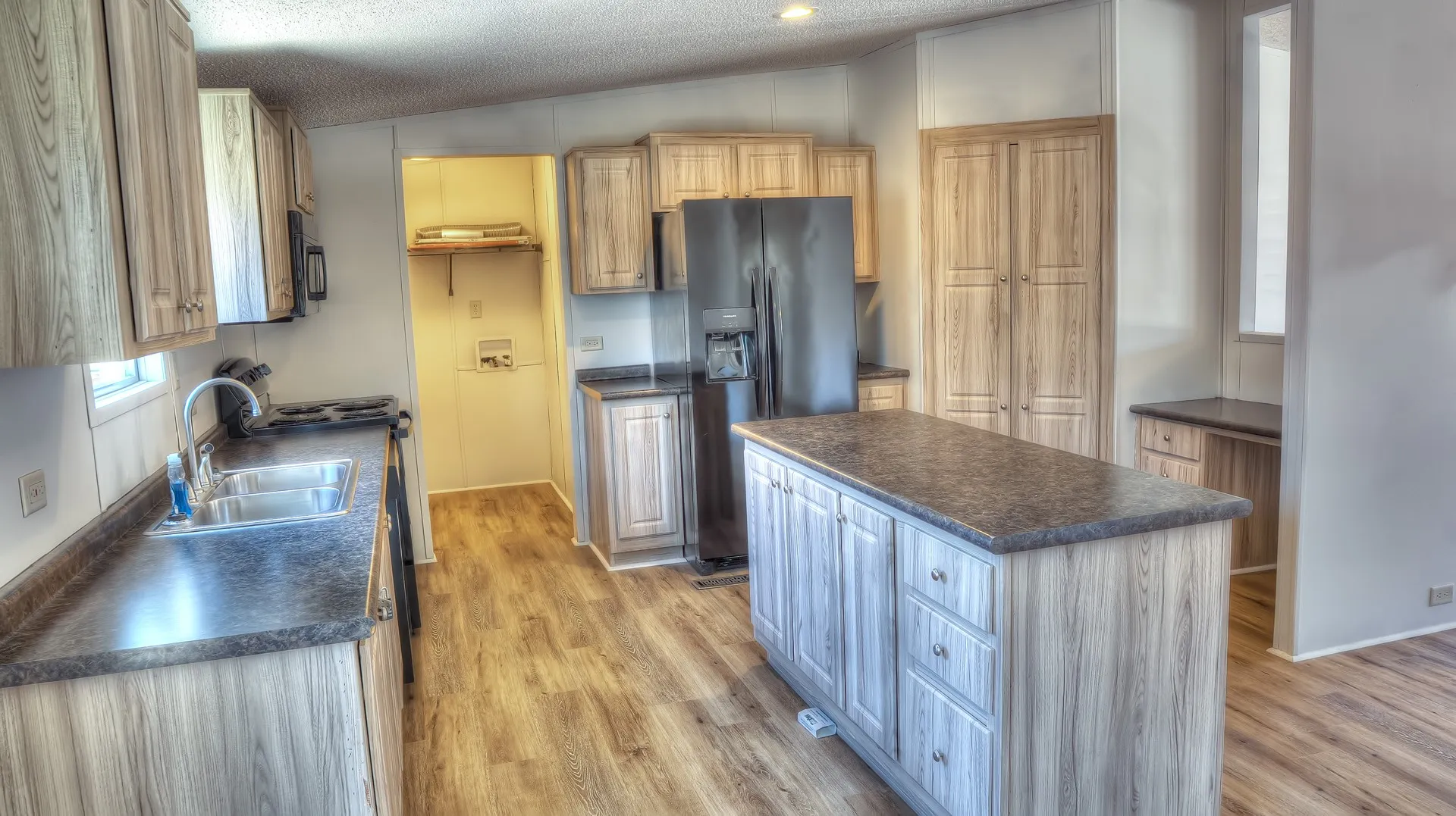 Kitchen featuring a central island with wood-finish cabinetry, dark countertops, and wood-finish flooring