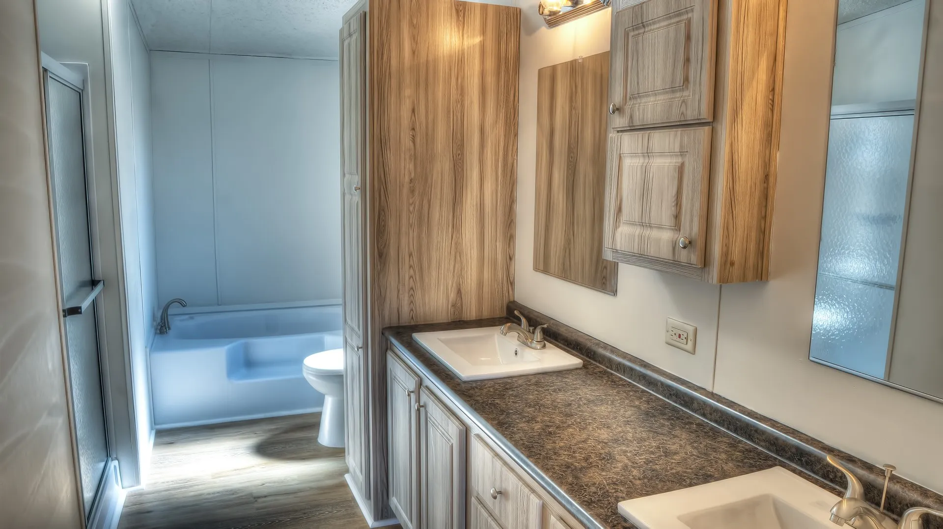Bathroom featuring a double vanity with integrated sinks, wood-finish cabinetry, a tub-shower combination, and wood-finish flooring