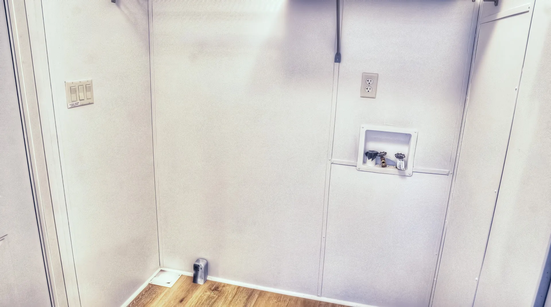 Dedicated utility space featuring wood-finish flooring and white paneled walls