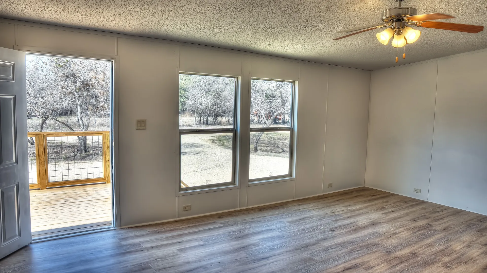 Spacious interior featuring wood-finish flooring, white walls, and a ceiling fan with integrated lighting