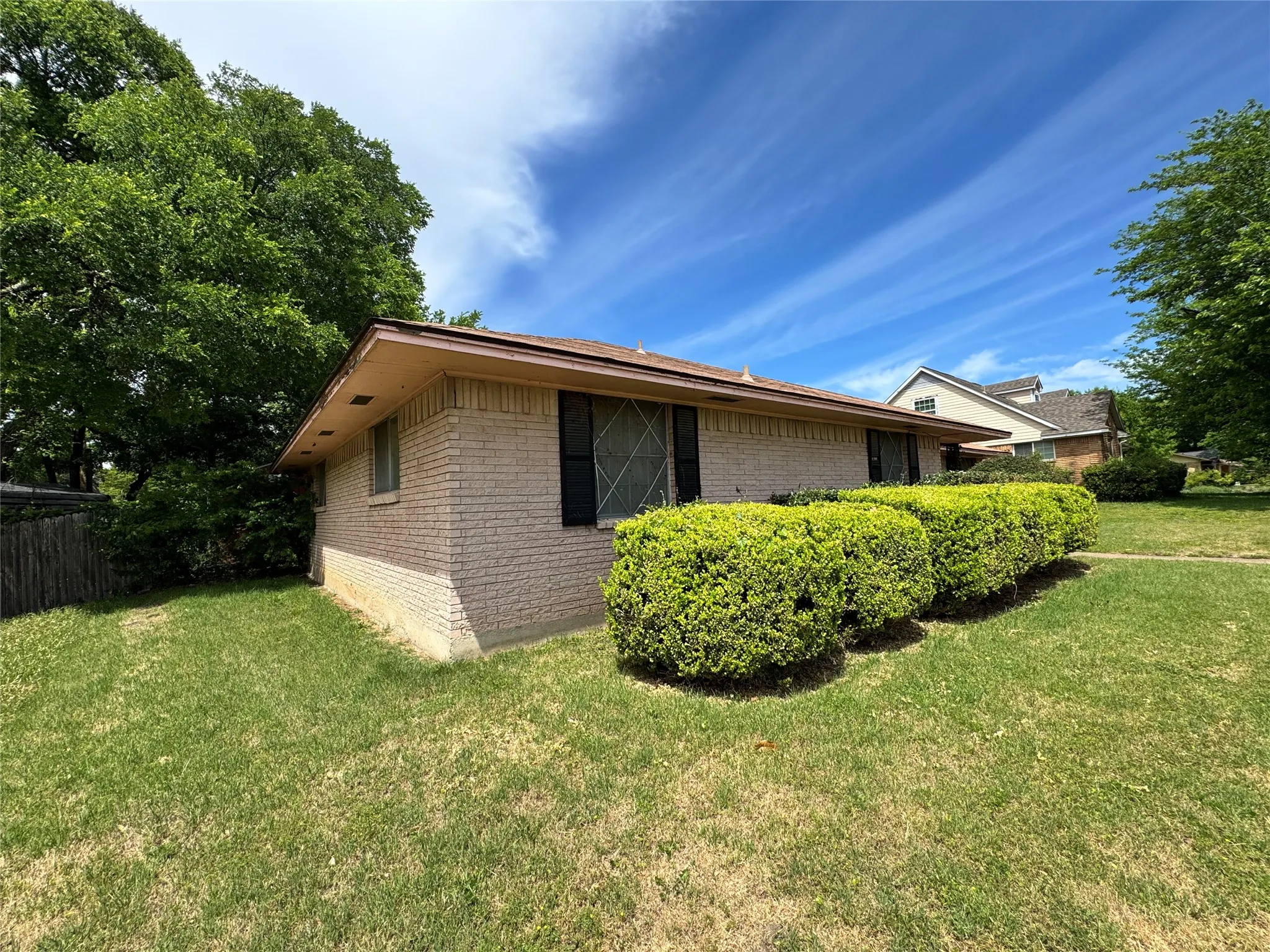 Expansive backyard featuring a lawn, a covered patio with support columns, and a detached storage shed with double doors