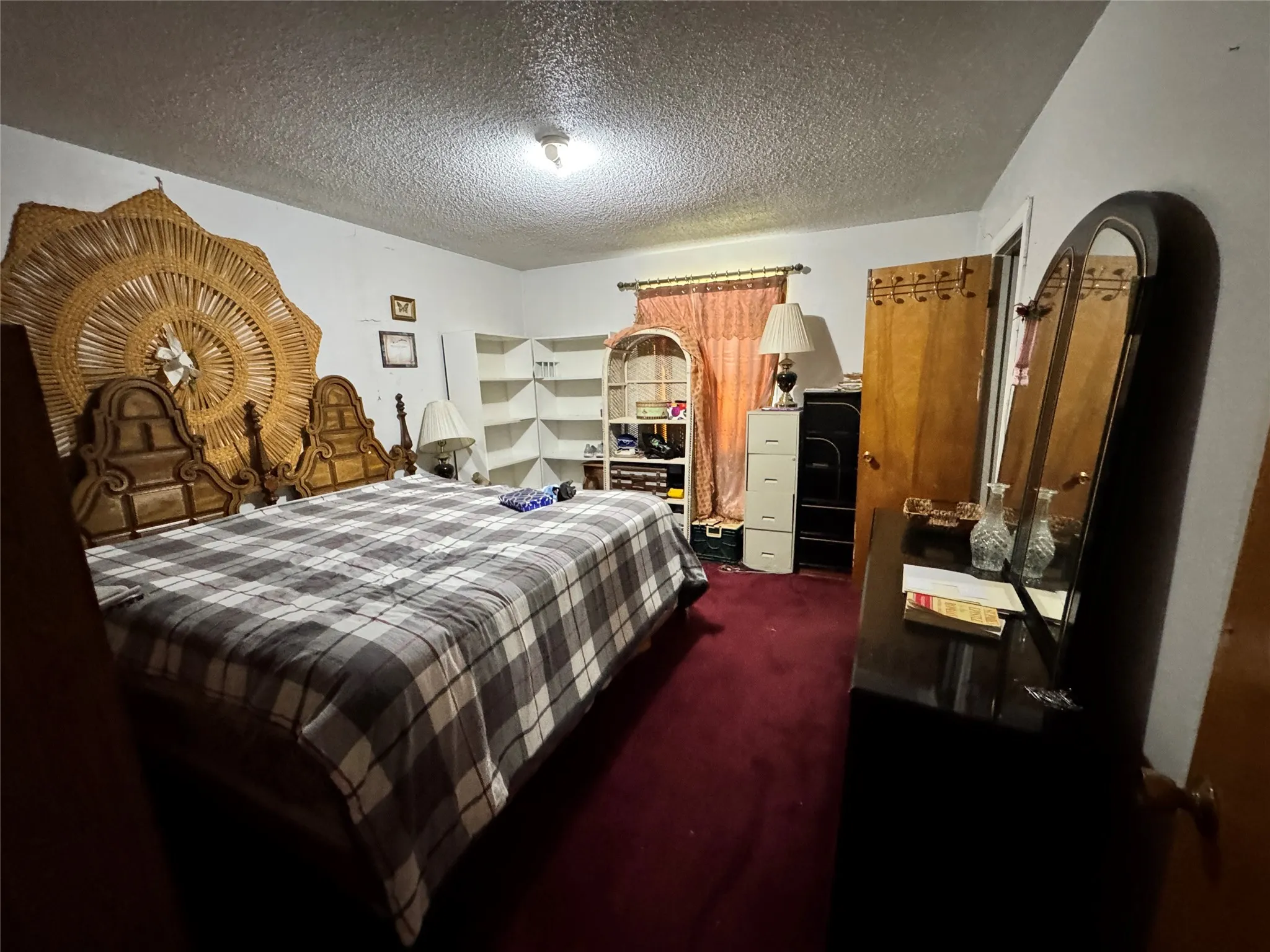Room featuring a neutral wall color, red carpet flooring, and a textured ceiling