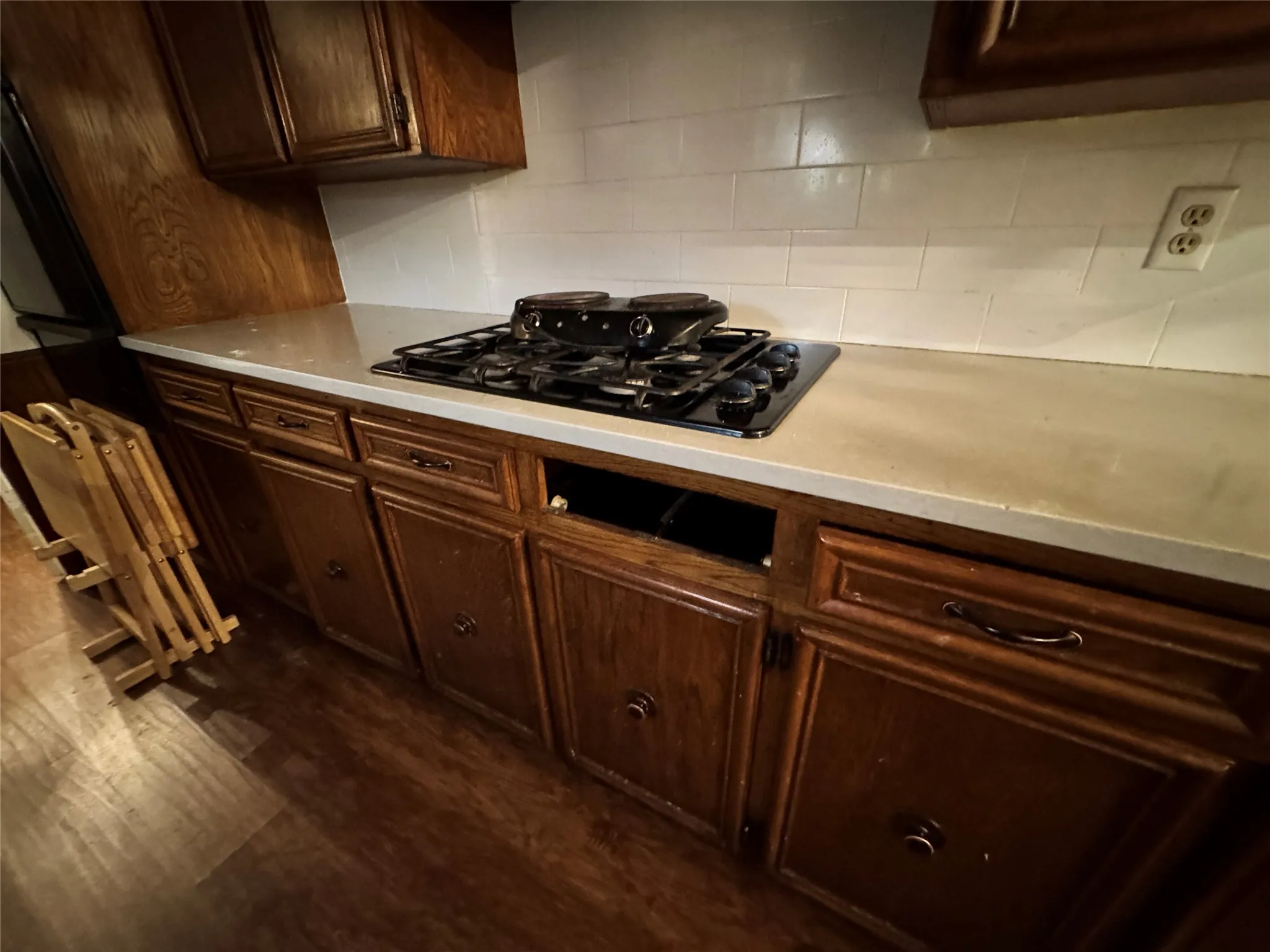 Kitchen featuring wood cabinetry, a gas cooktop, light-toned countertops, and a white subway tile backsplash