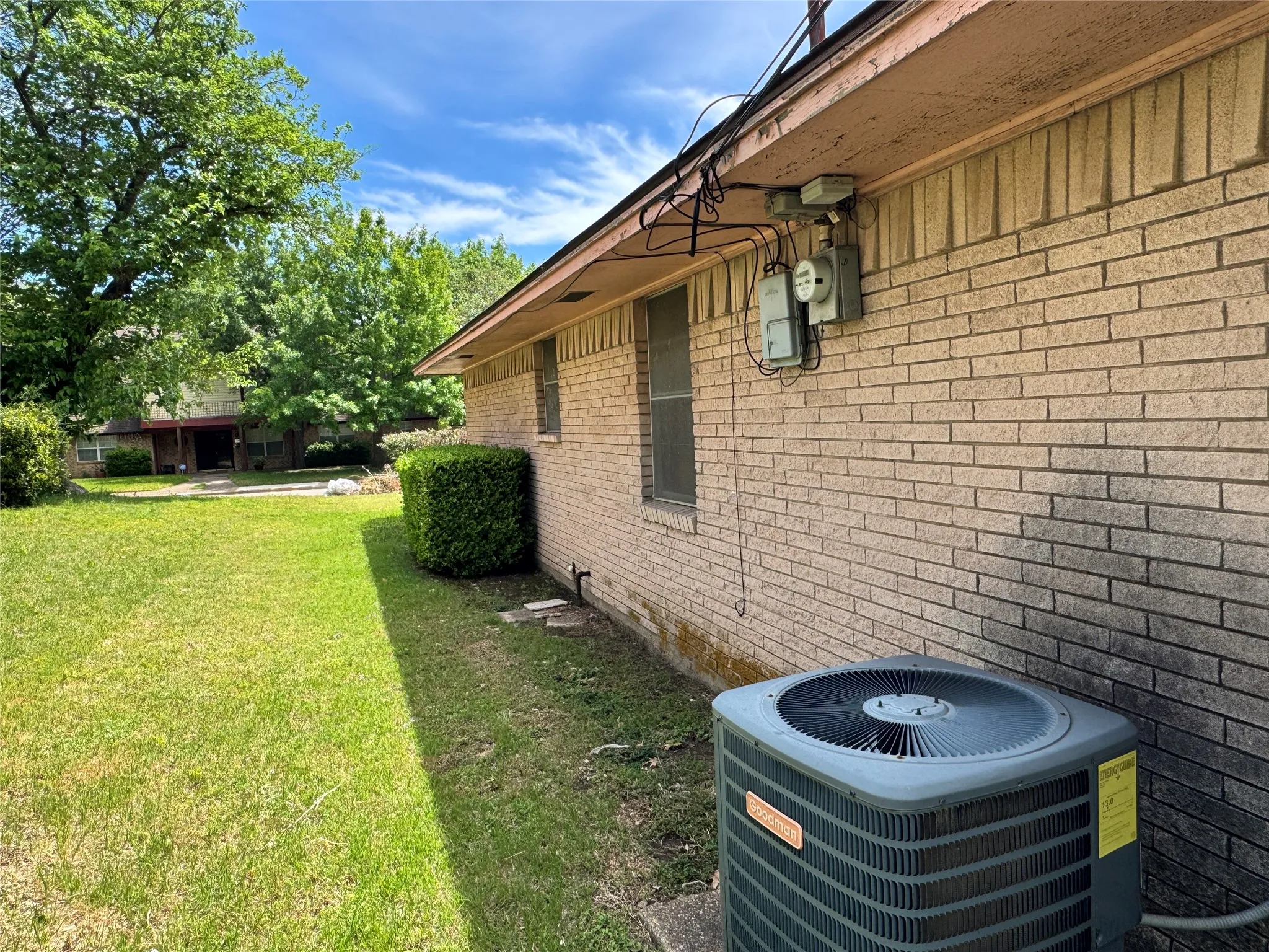 Exterior brick siding with a landscaped bush and an air conditioning unit