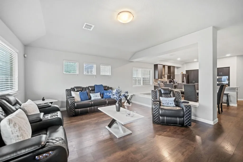 Spacious living area featuring wood-finish flooring, light-toned walls, and recessed lighting