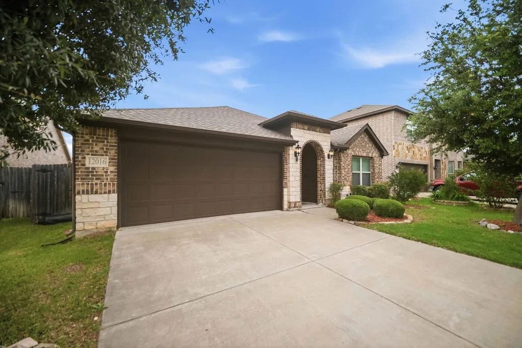 Brick and stone facade residence featuring an arched entry, a two-car garage, and a concrete driveway