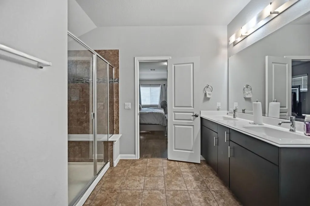 Bathroom featuring a dual vanity with white countertops and undermount sinks, a large mirror, and overhead strip lighting