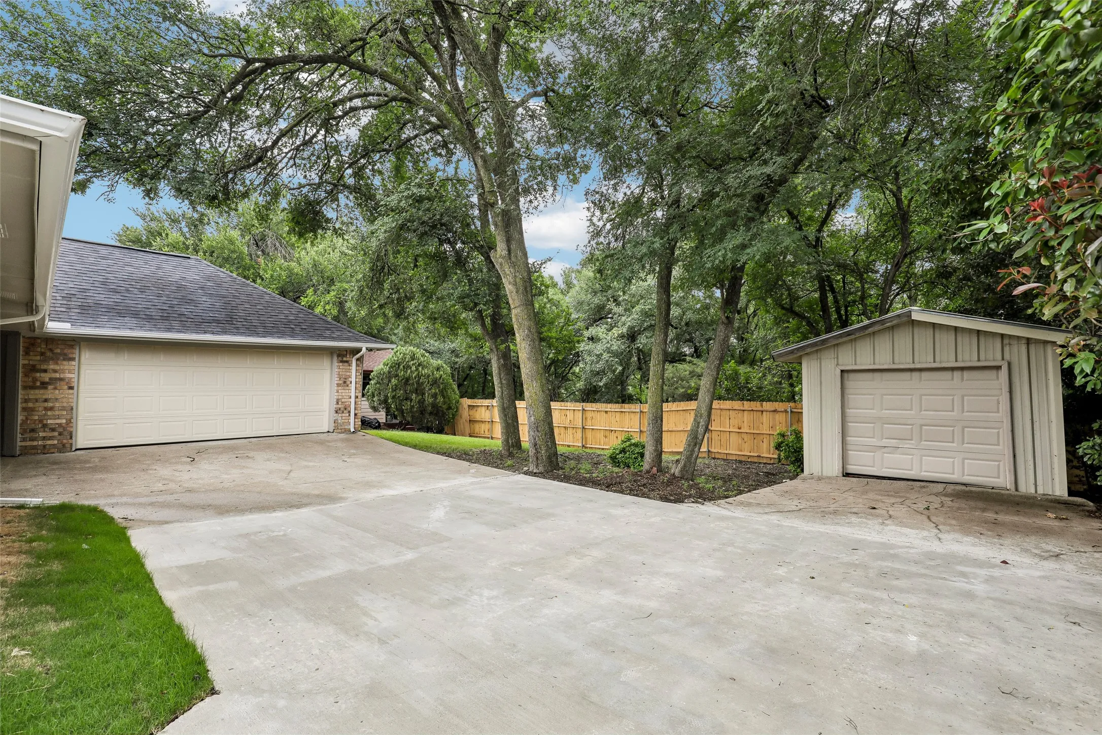 Expansive concrete driveway with a two-car garage and a detached single-car garage