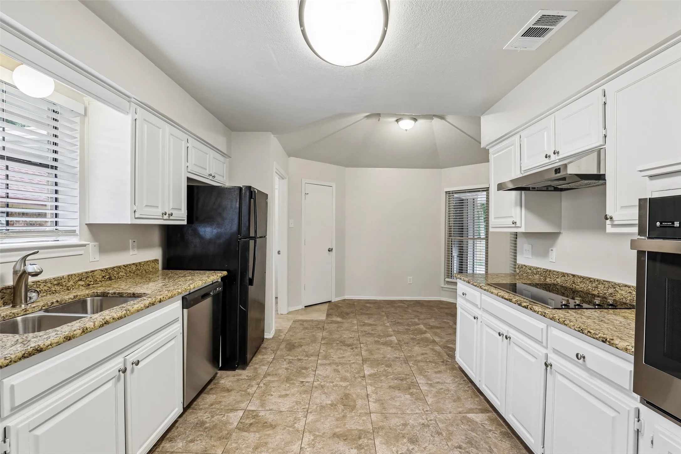Kitchen featuring white cabinetry, granite-style countertops, stainless steel sink, tile flooring, and integrated stainless steel appliances