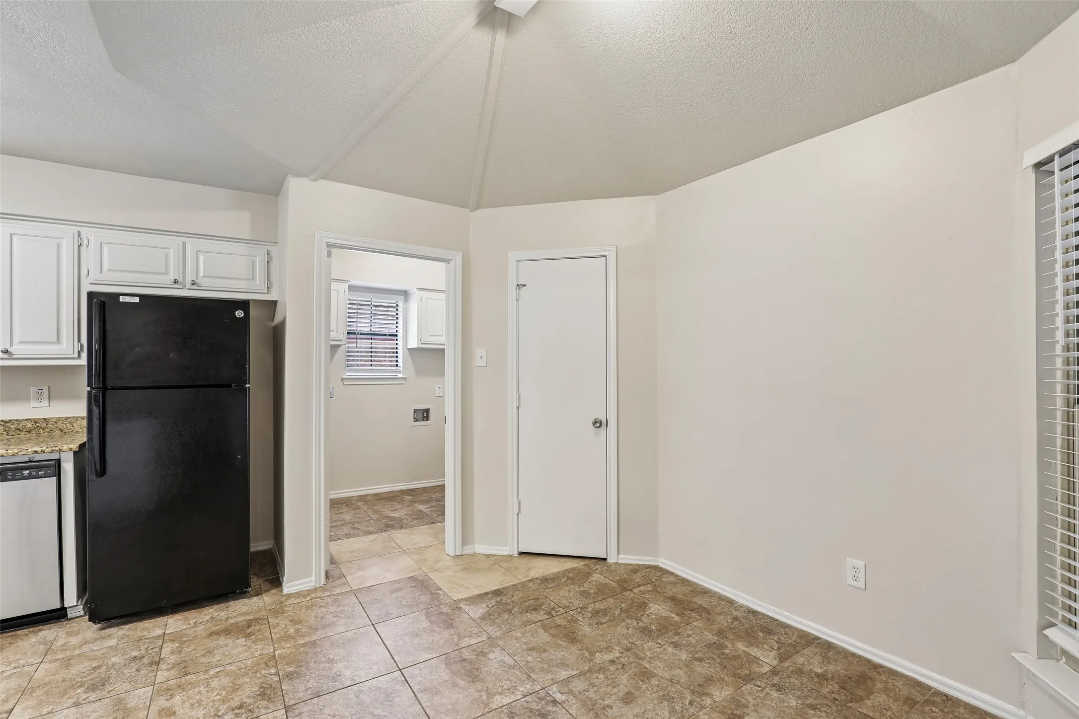Kitchen area featuring white cabinetry, a black refrigerator, and a dishwasher