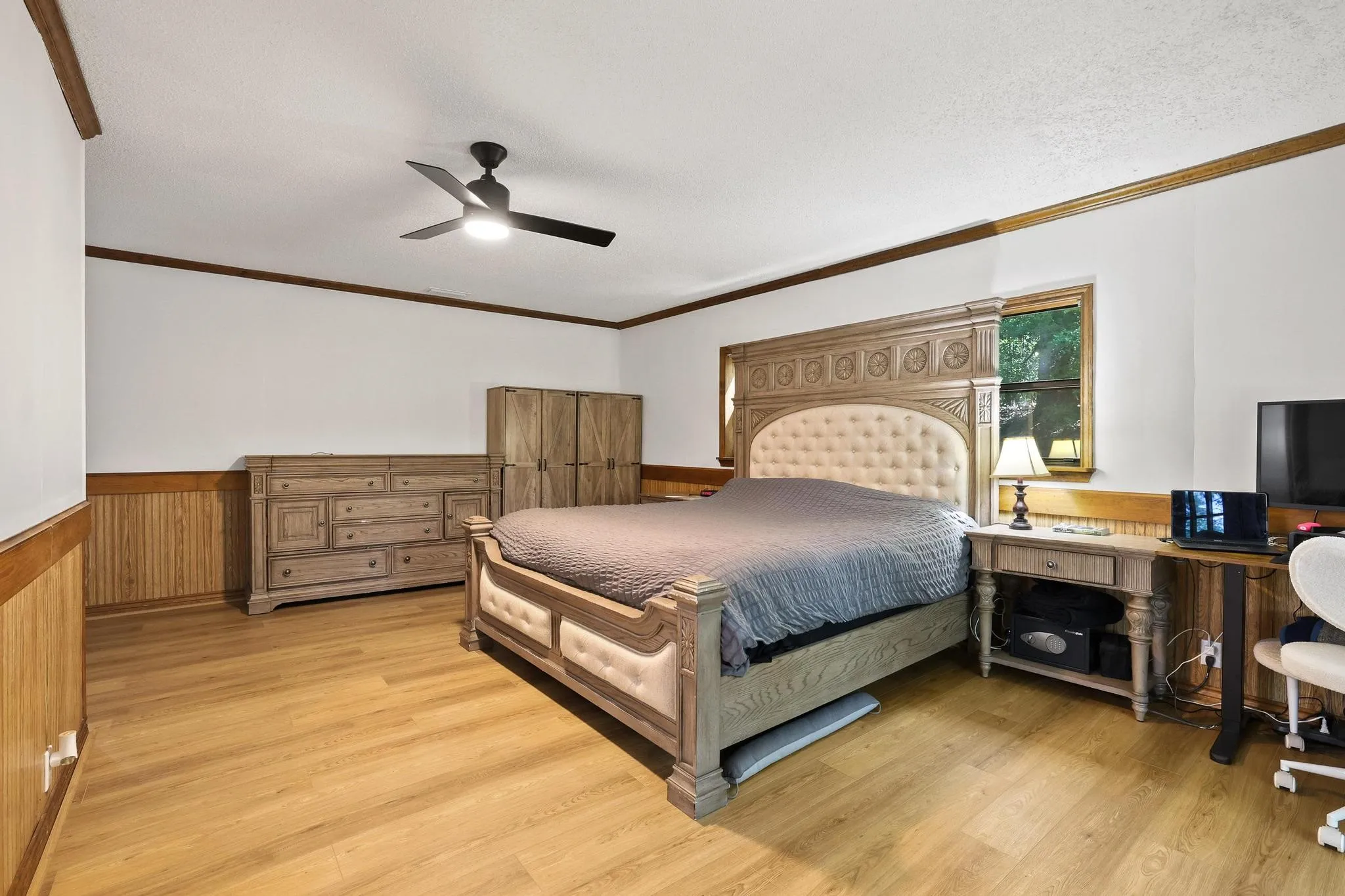 Spacious interior featuring wood-finish flooring, white walls, and wood wainscoting