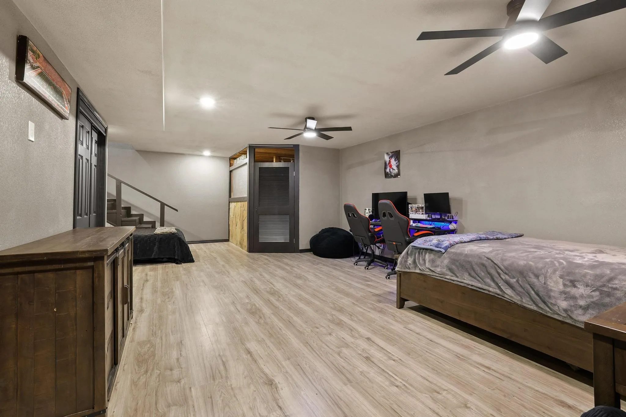 Spacious lower-level room featuring wood-finish flooring, recessed lighting, and dual ceiling fans
