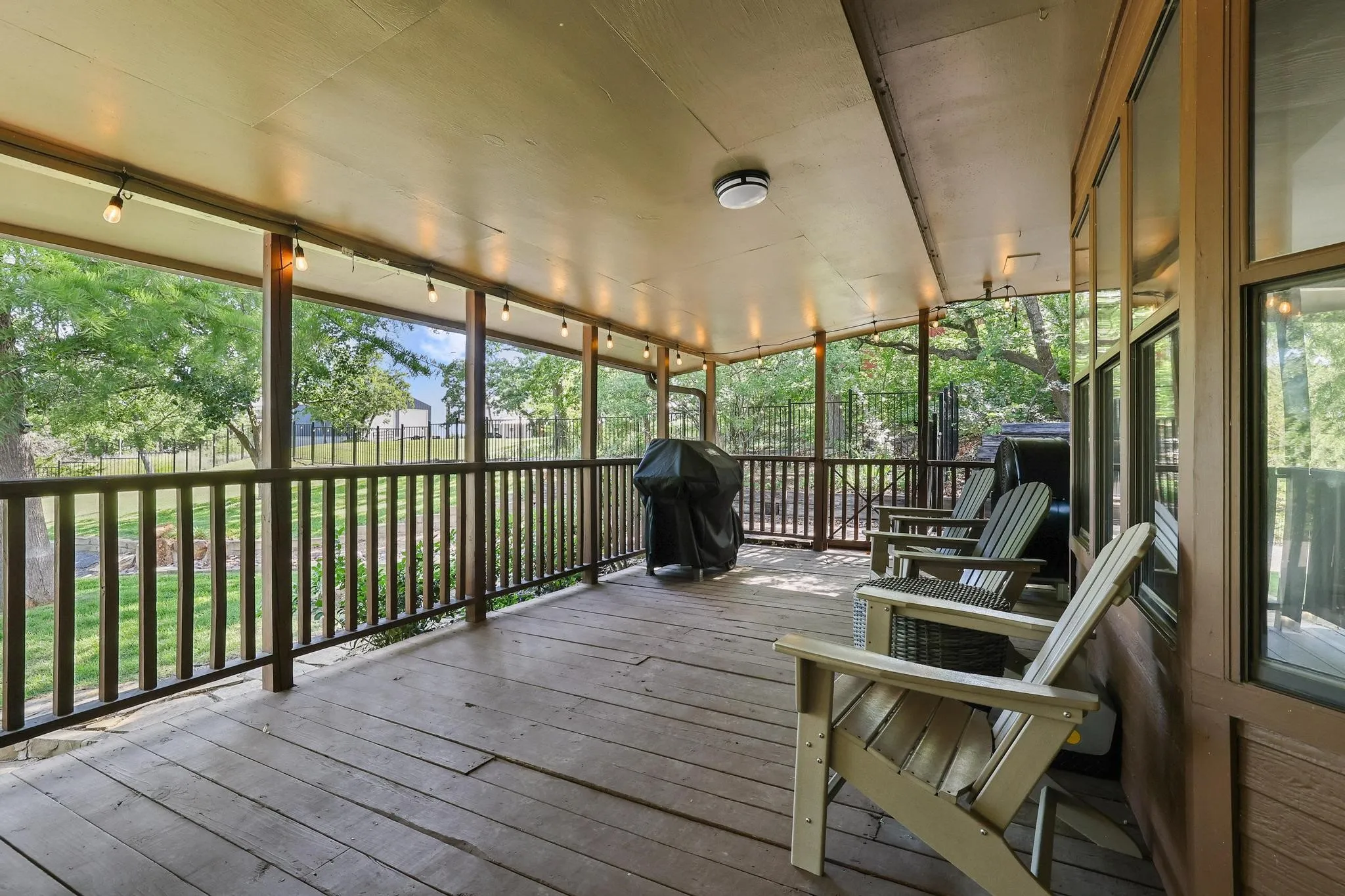 Covered outdoor patio with wood-finish flooring, wood railings, and an expansive overhead structure