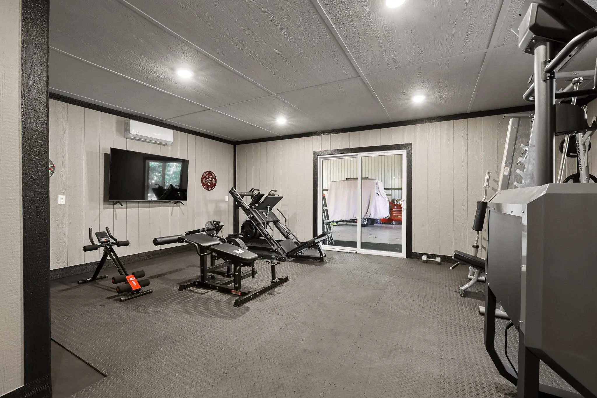 Versatile interior space featuring light-colored vertical paneling, recessed lighting, and dark trim details