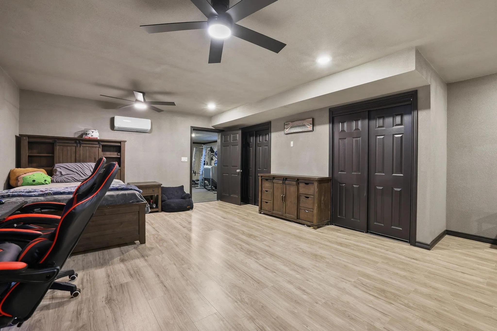 Spacious room featuring light wood-finish flooring, recessed lighting, and two ceiling fans with integrated lighting
