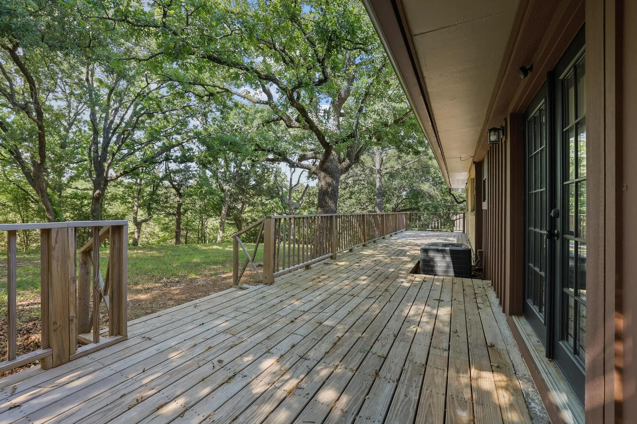 Expansive wood deck with a full wood railing overlooking a lush, tree-filled landscape