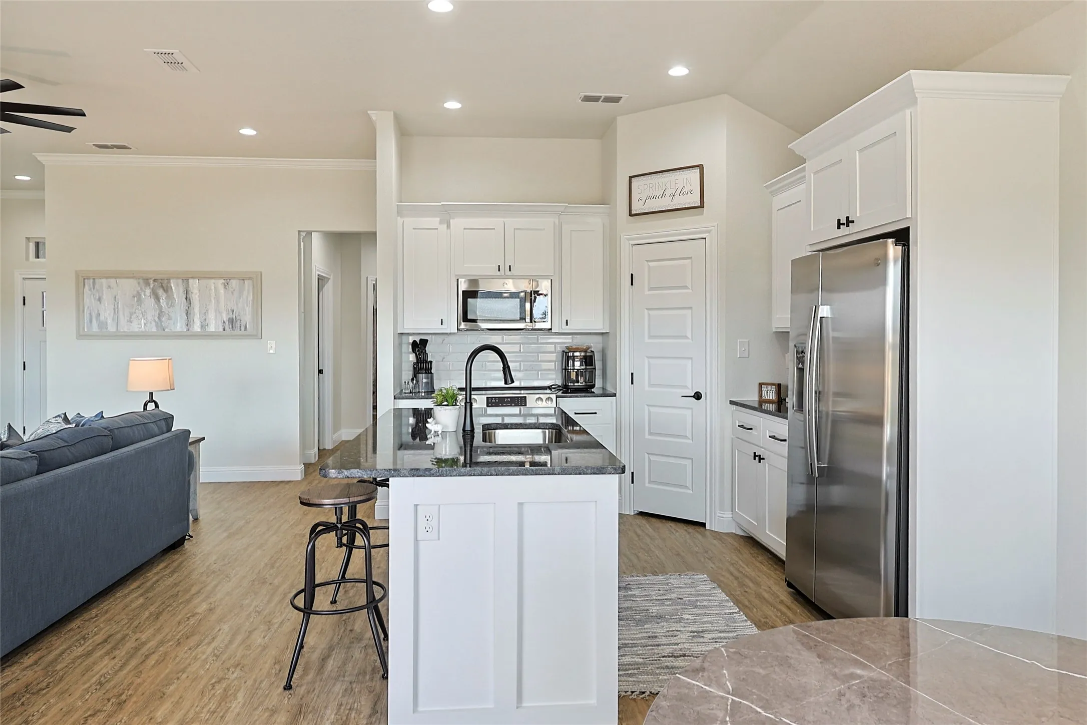 Kitchen with white cabinetry, stainless steel appliances, dark countertops, and a subway tile backsplash