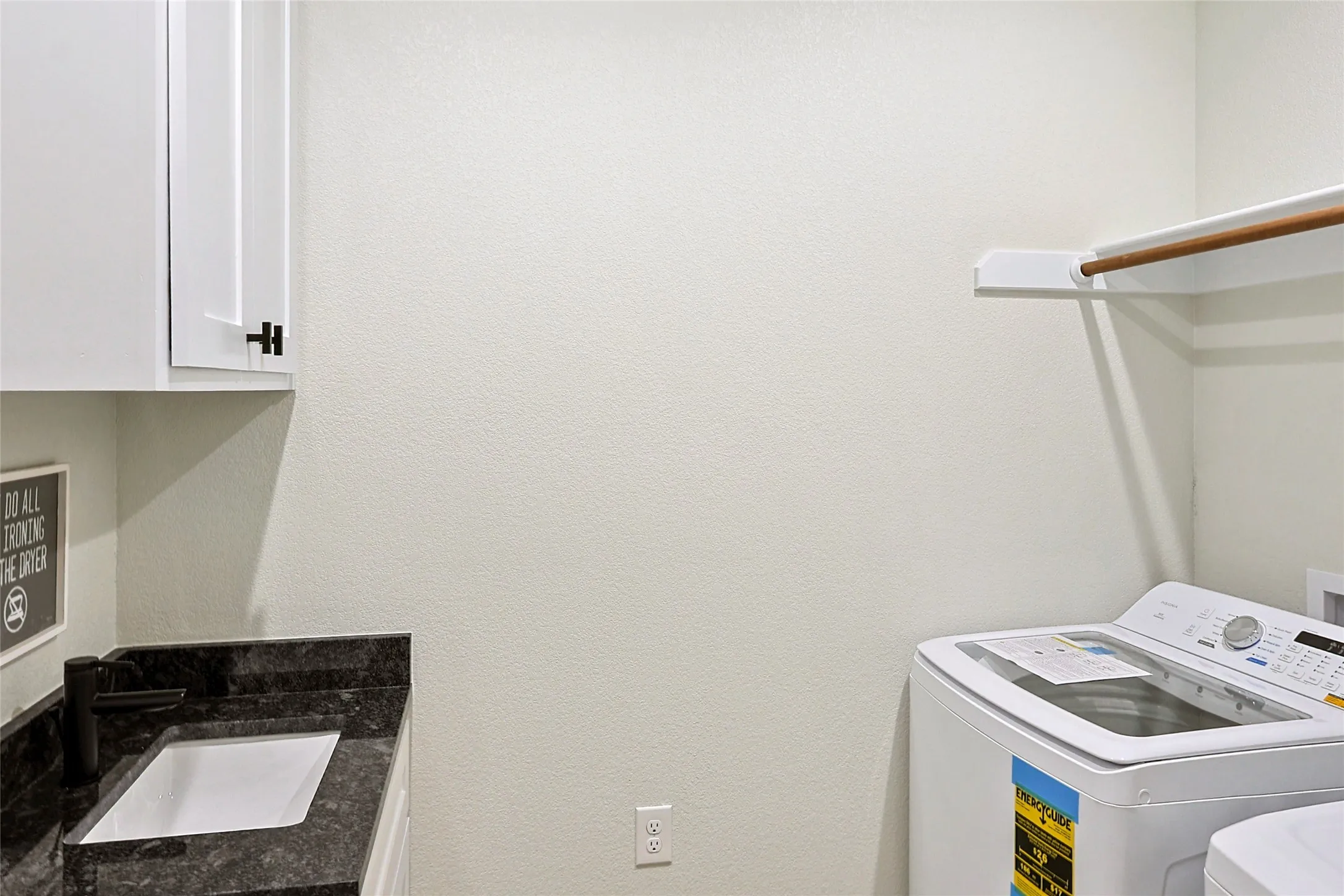 Laundry area featuring a built-in sink with a dark granite-style countertop and backsplash