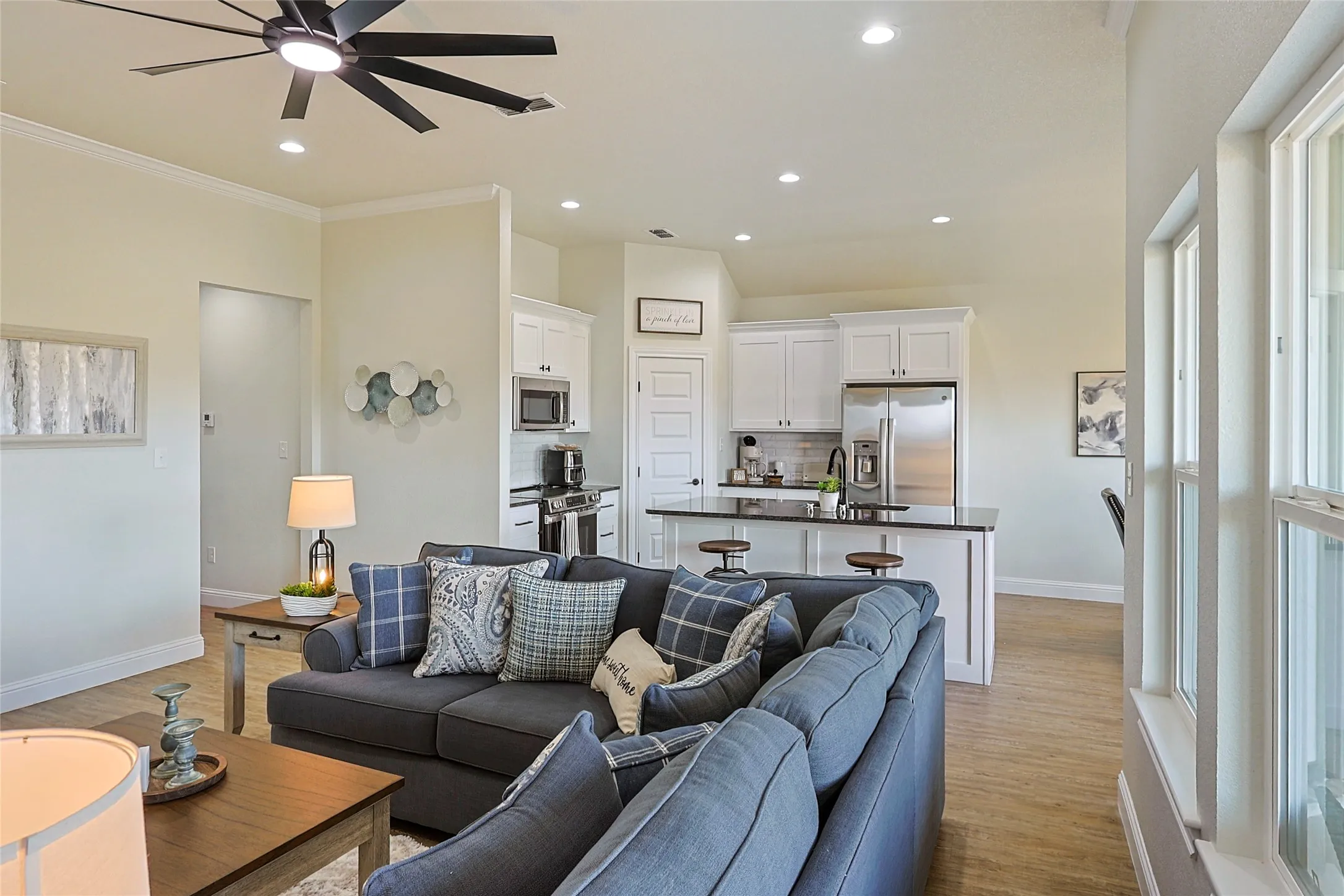 Open-concept living area featuring wood-finish flooring, recessed lighting, and a modern ceiling fan
