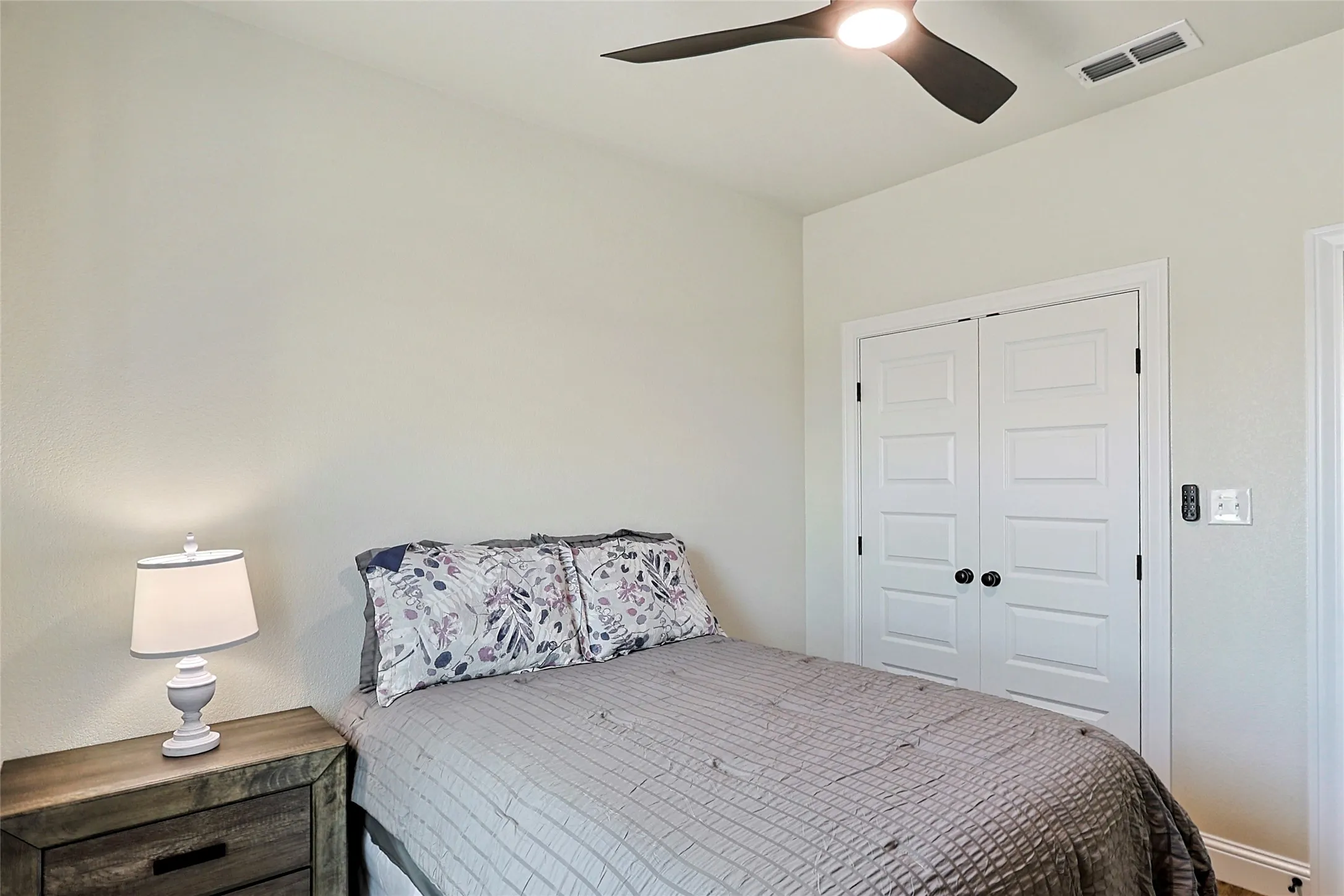 Neutral wall finish with a built-in closet featuring white panel doors and black hardware