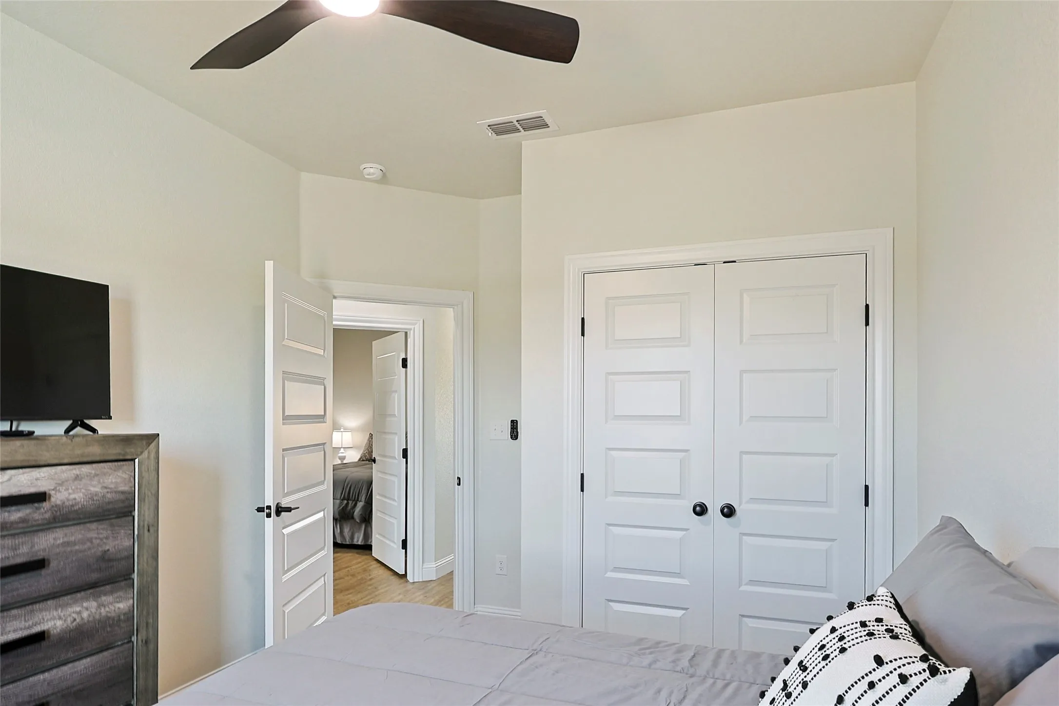 Bedroom featuring light-toned walls, a ceiling fan, and a built-in closet with panel doors