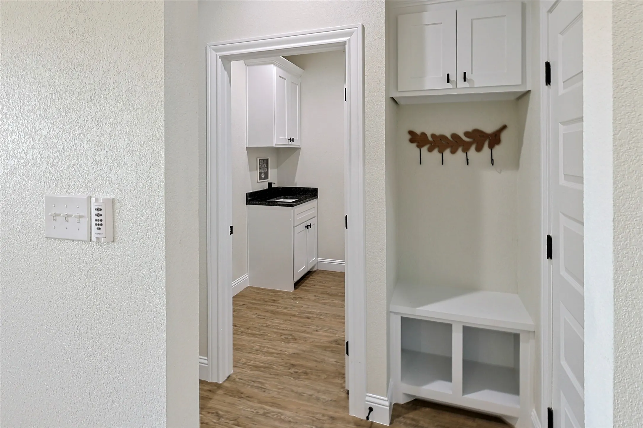 Built-in mudroom bench with cubbies, upper cabinetry, and a coat rack