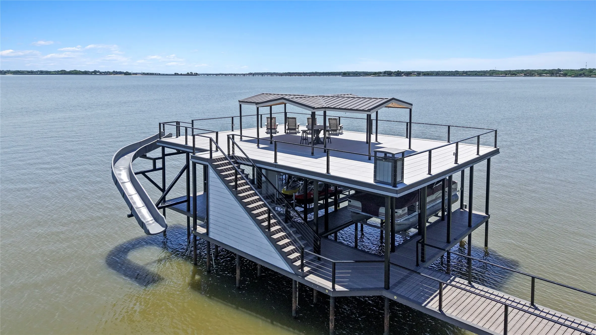 New custom boathouse designed for entertaining with composite decking, wet bar, covered seating, epic waterslide and cool deck!