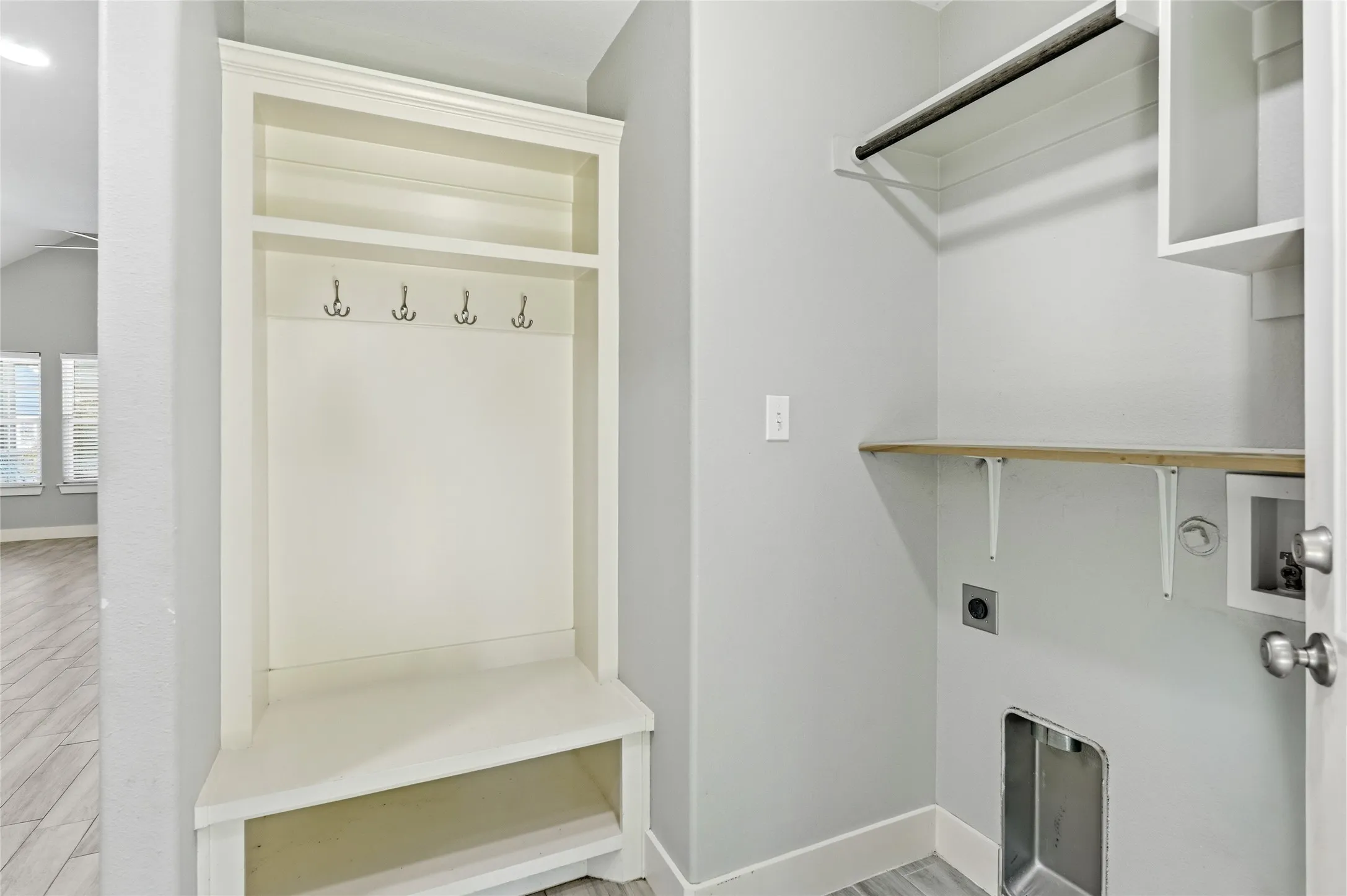 Built-in mudroom bench with coat hooks and overhead shelving