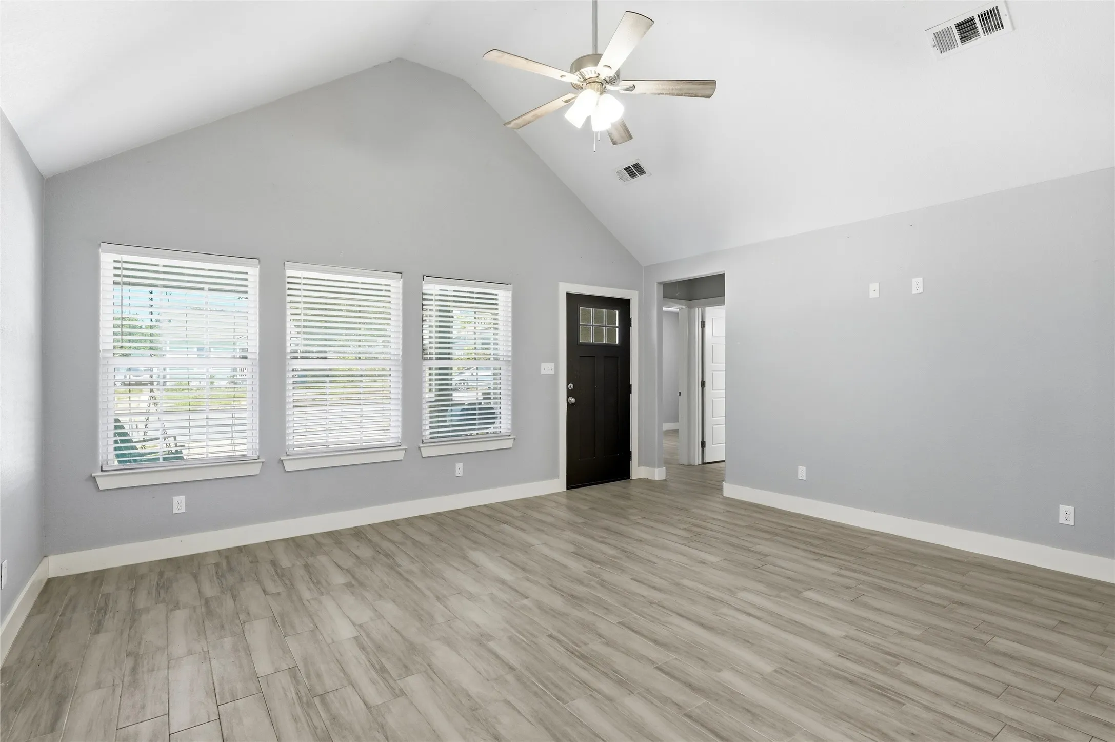 Spacious living area featuring a vaulted ceiling and ceramic tile flooring.