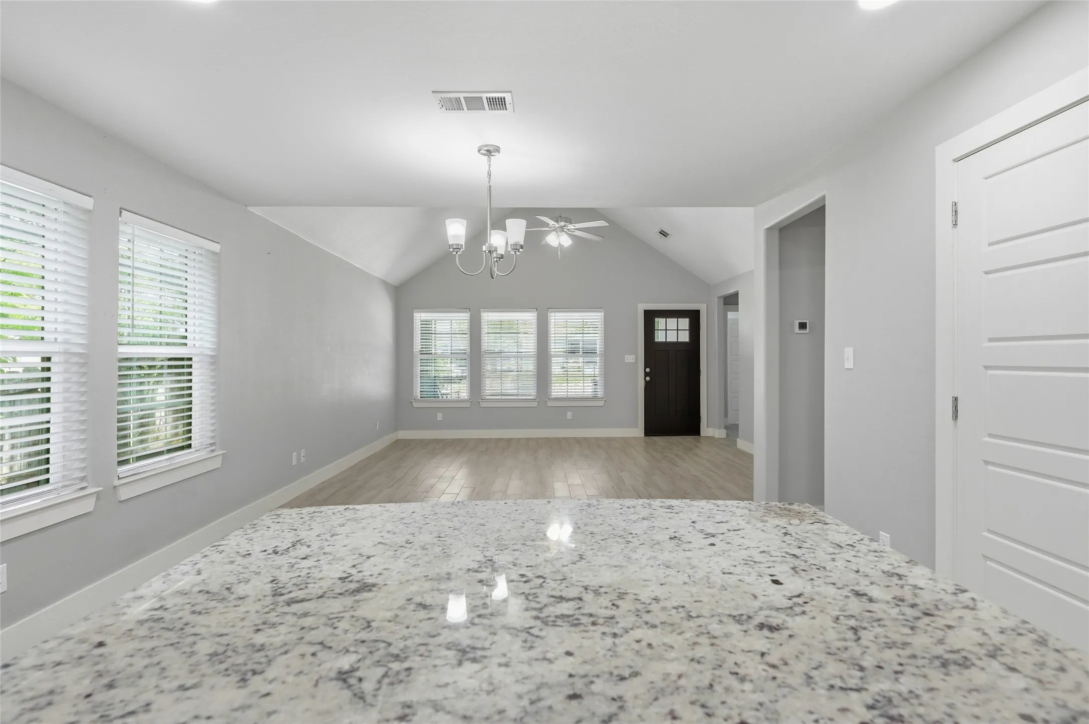 Granite-finish countertop with a bright interior, vaulted ceiling, ceramic tile flooring, and multiple windows